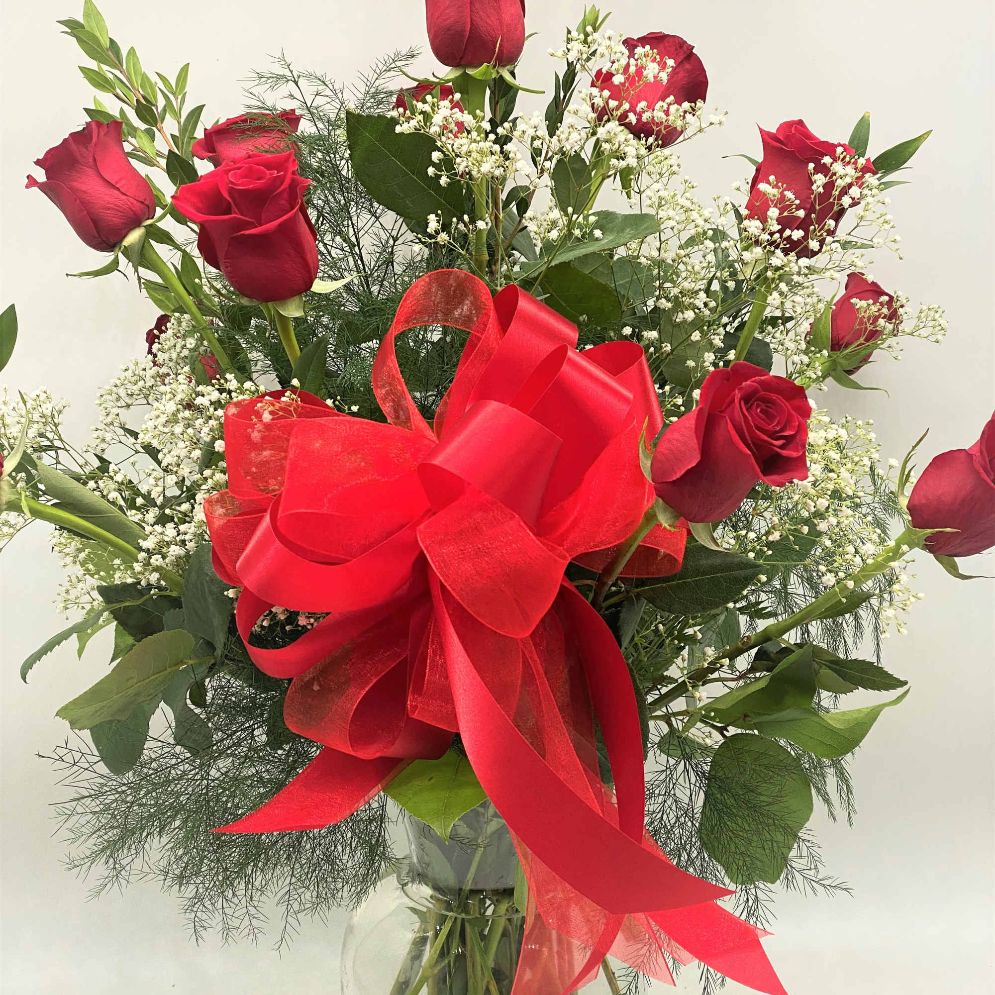 Red roses with baby's breath in a glass vase and red bow