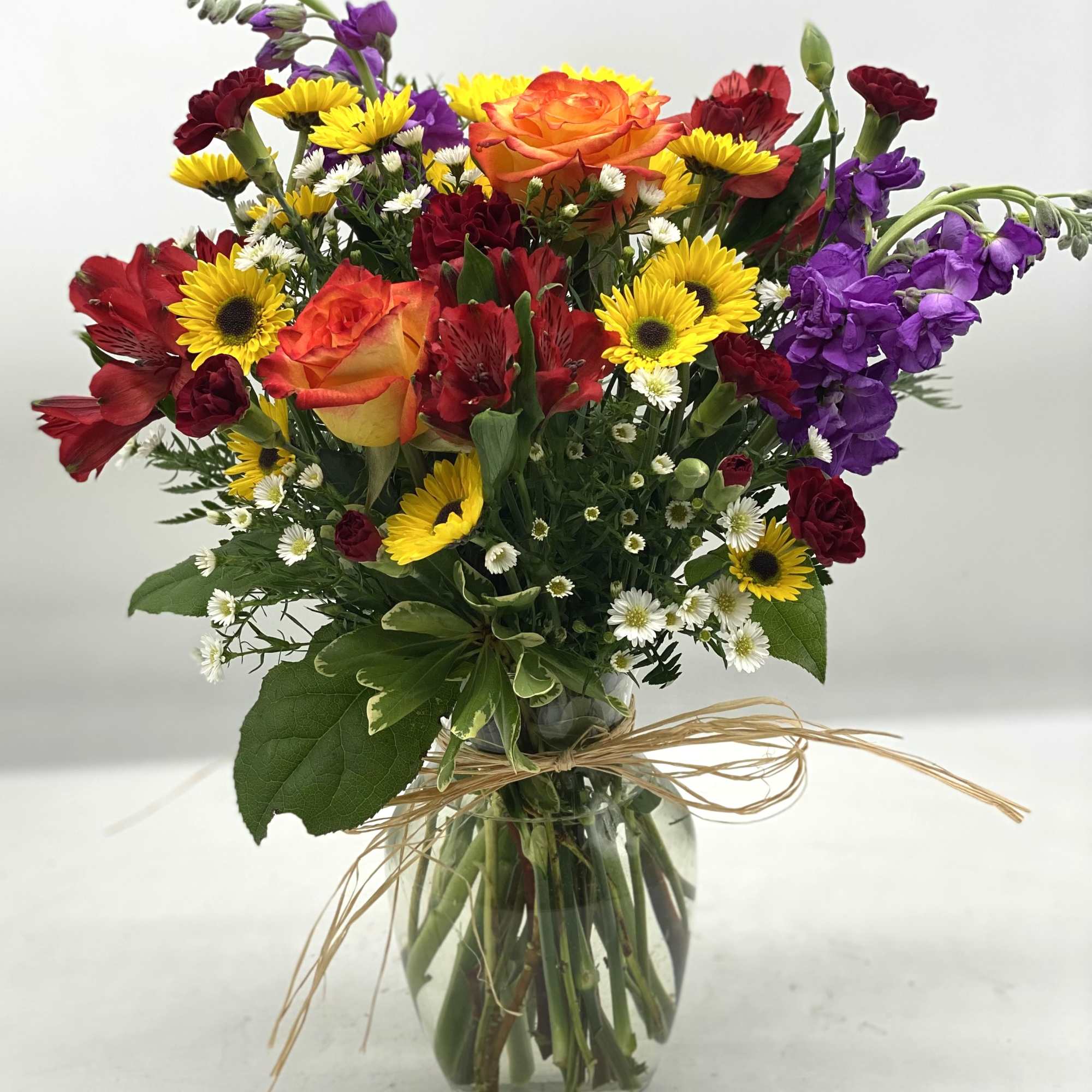 A mix of fall hues in a clear, glass vase finished off