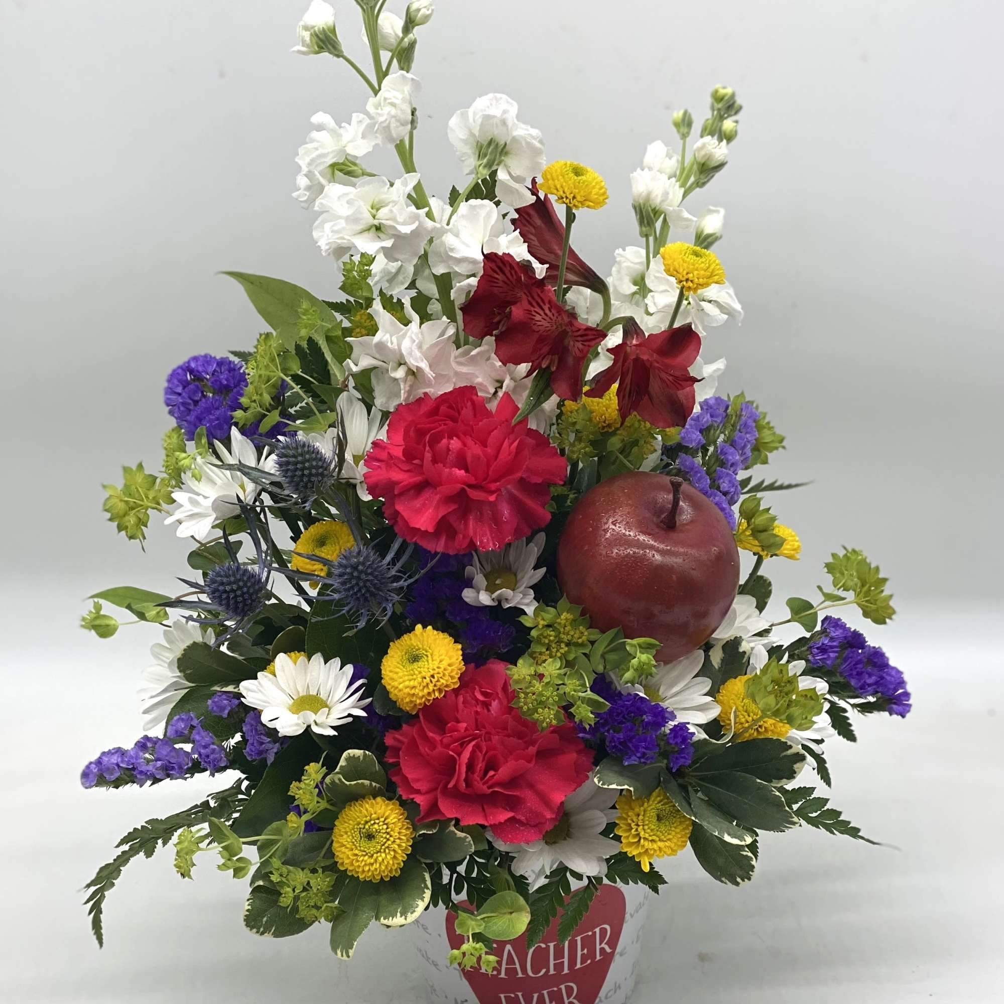 Mixed bouquet in a decorative pot with red, white, yellow, and purple flowers