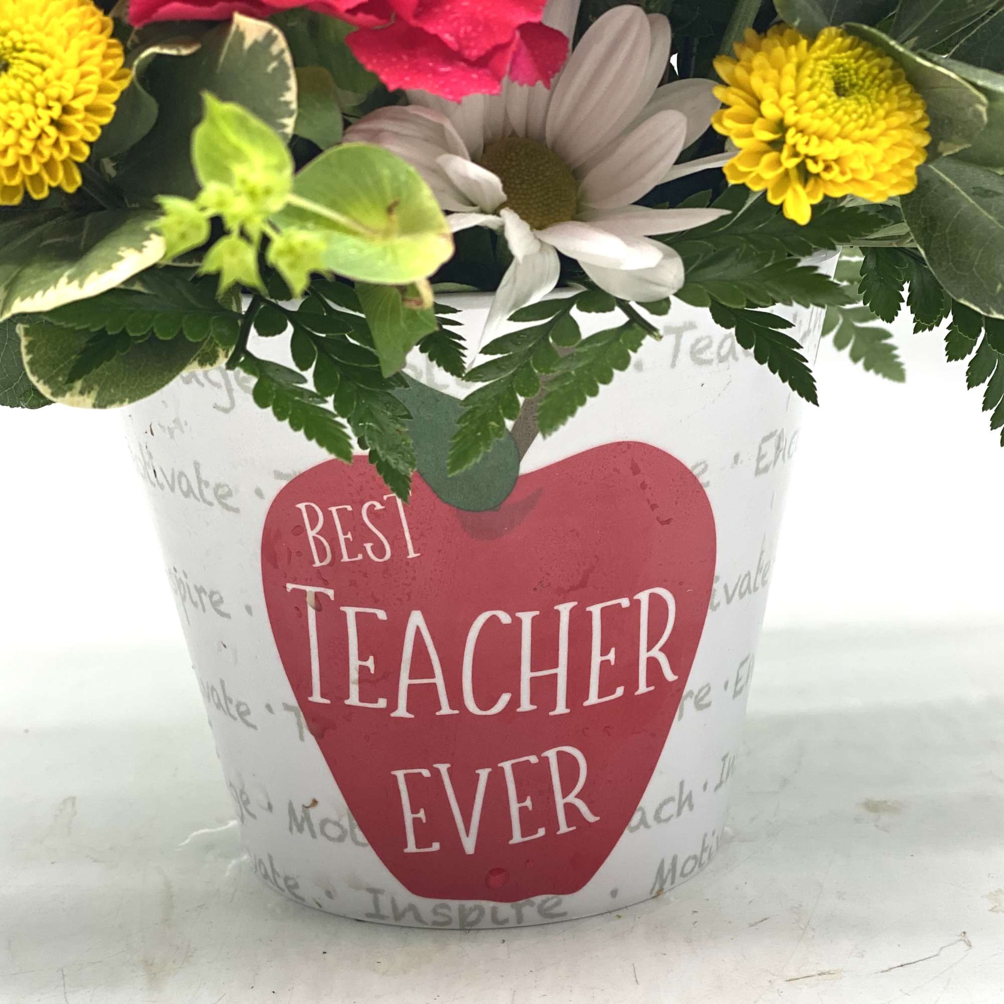 Mixed flowers in a white pot with a "Best Teacher Ever" label