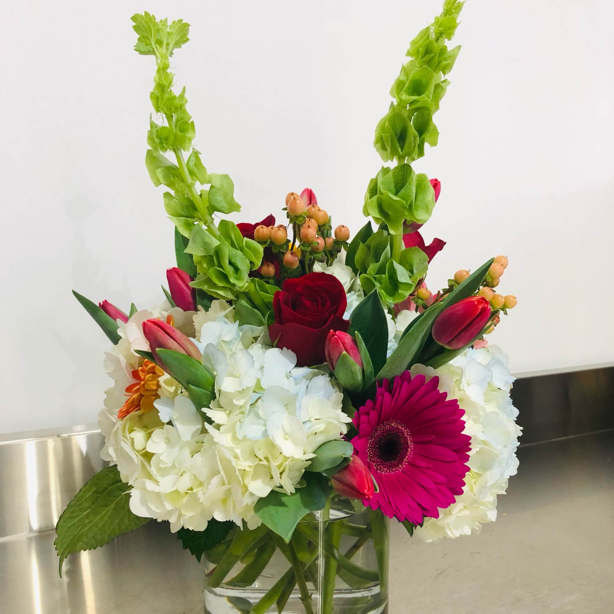 Beautiful design filled with blue and white hydrangea, tulips, gerbera daisies, bells, photo 2 of 2