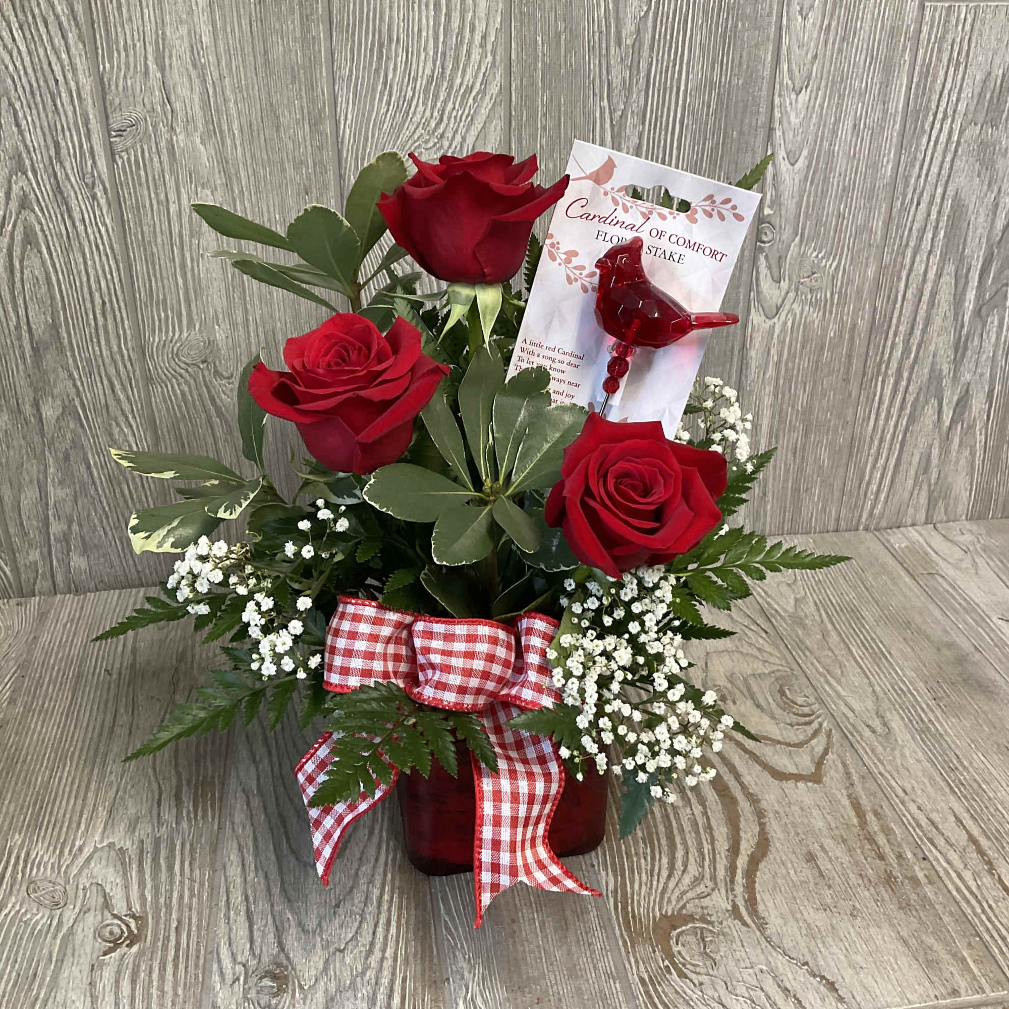 Three deep red roses rise from a compact cluster of delicate white