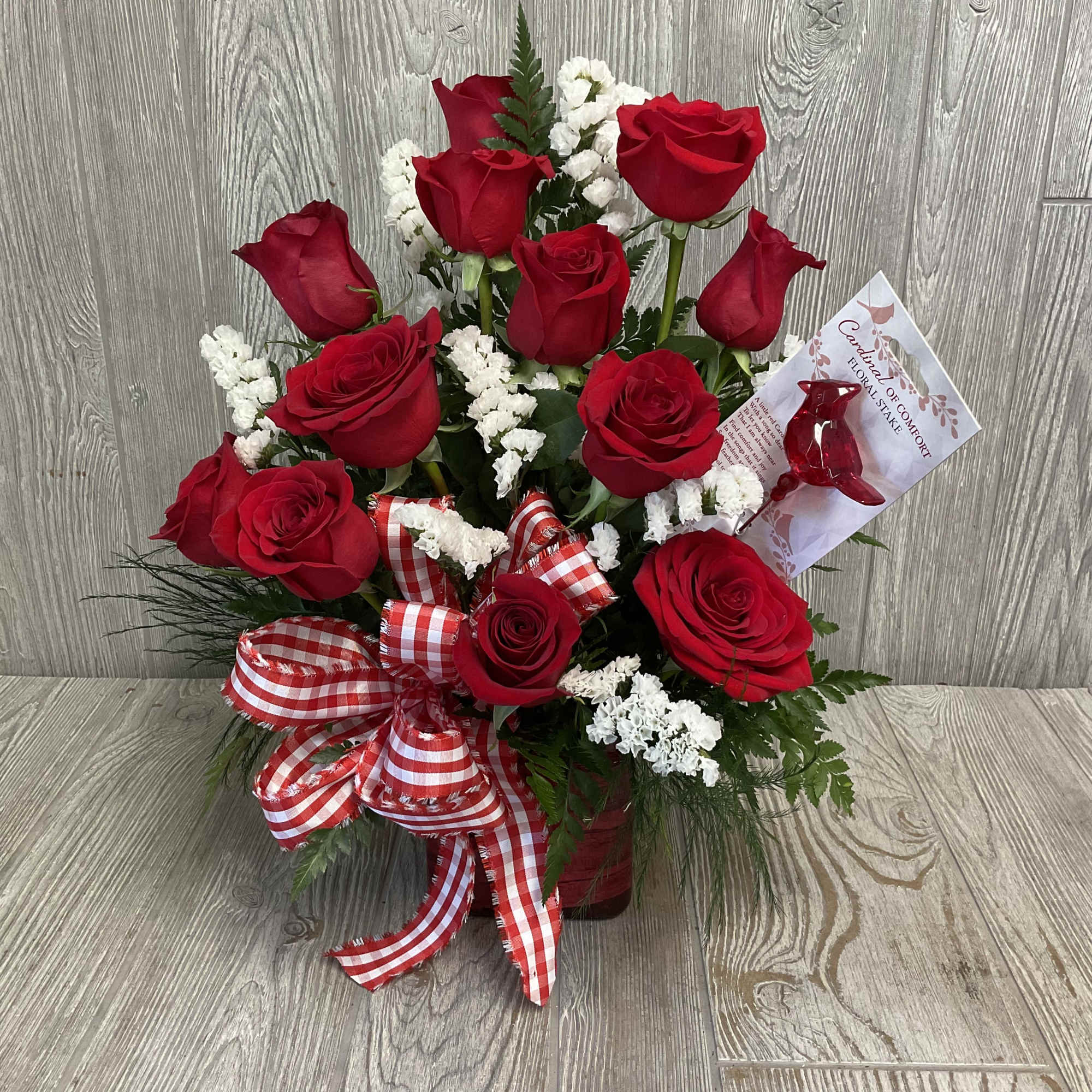 Three deep red roses rise from a compact cluster of delicate white