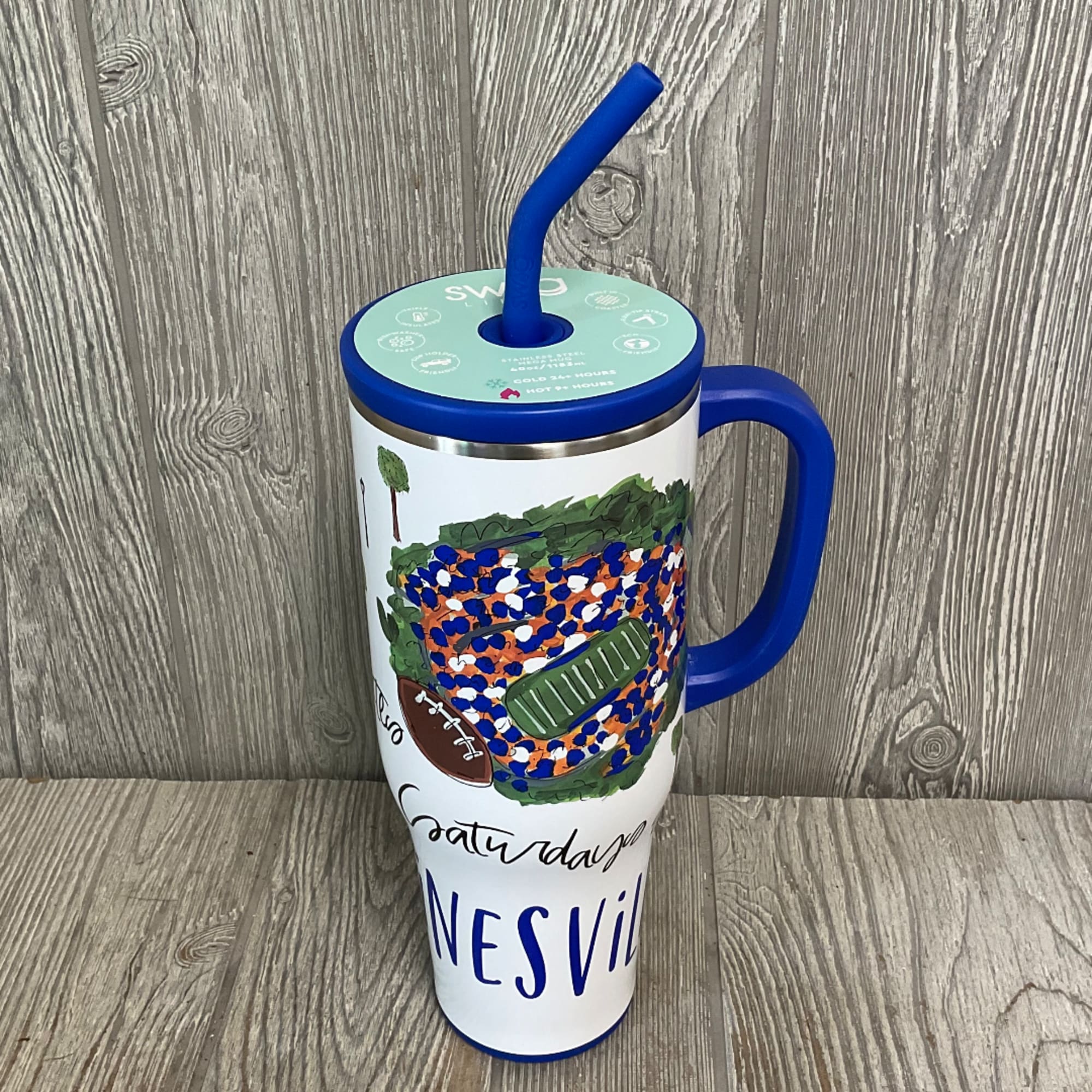 Blue handled tumbler with a straw and football-themed design