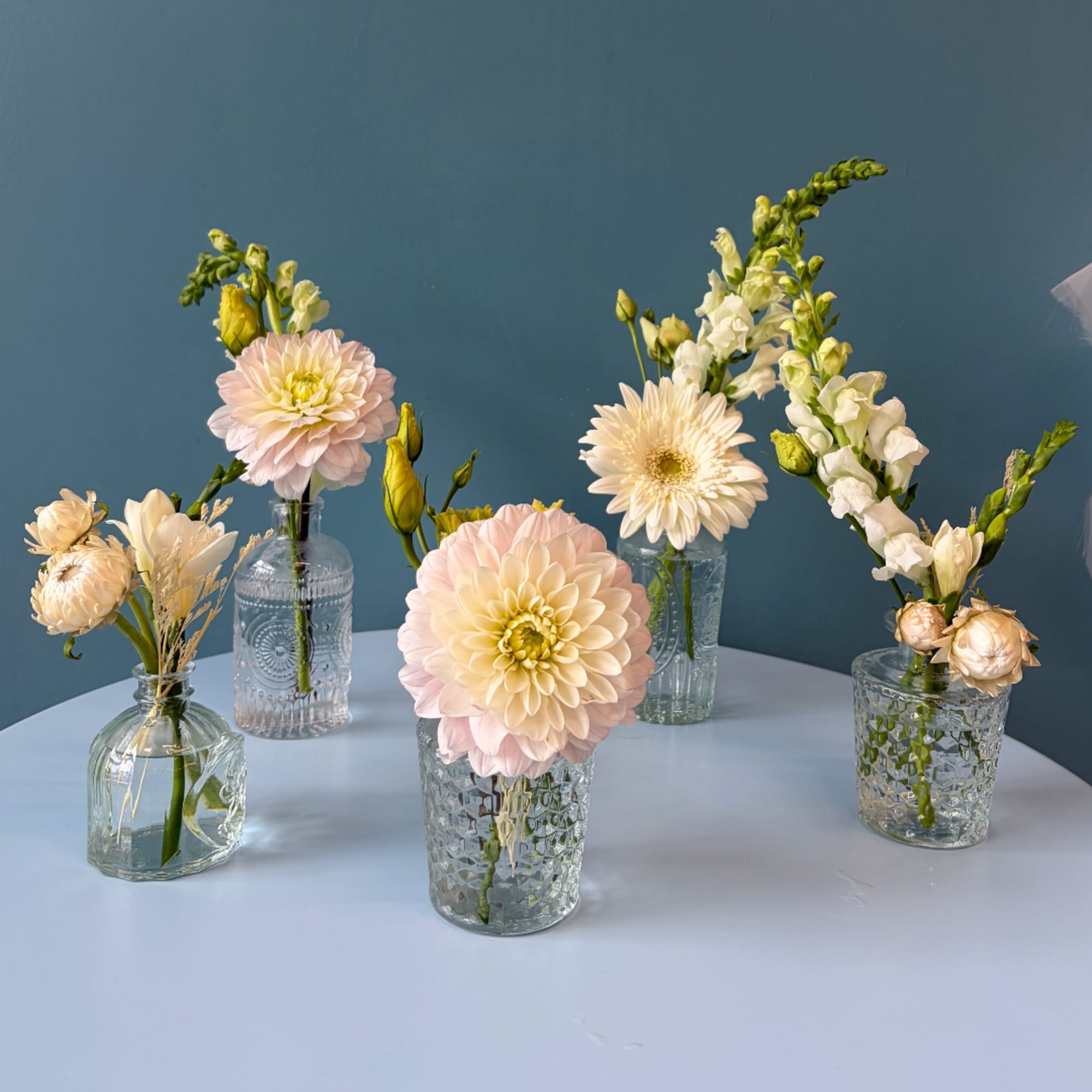 Pastel floral arrangements in clear glass vases on a table