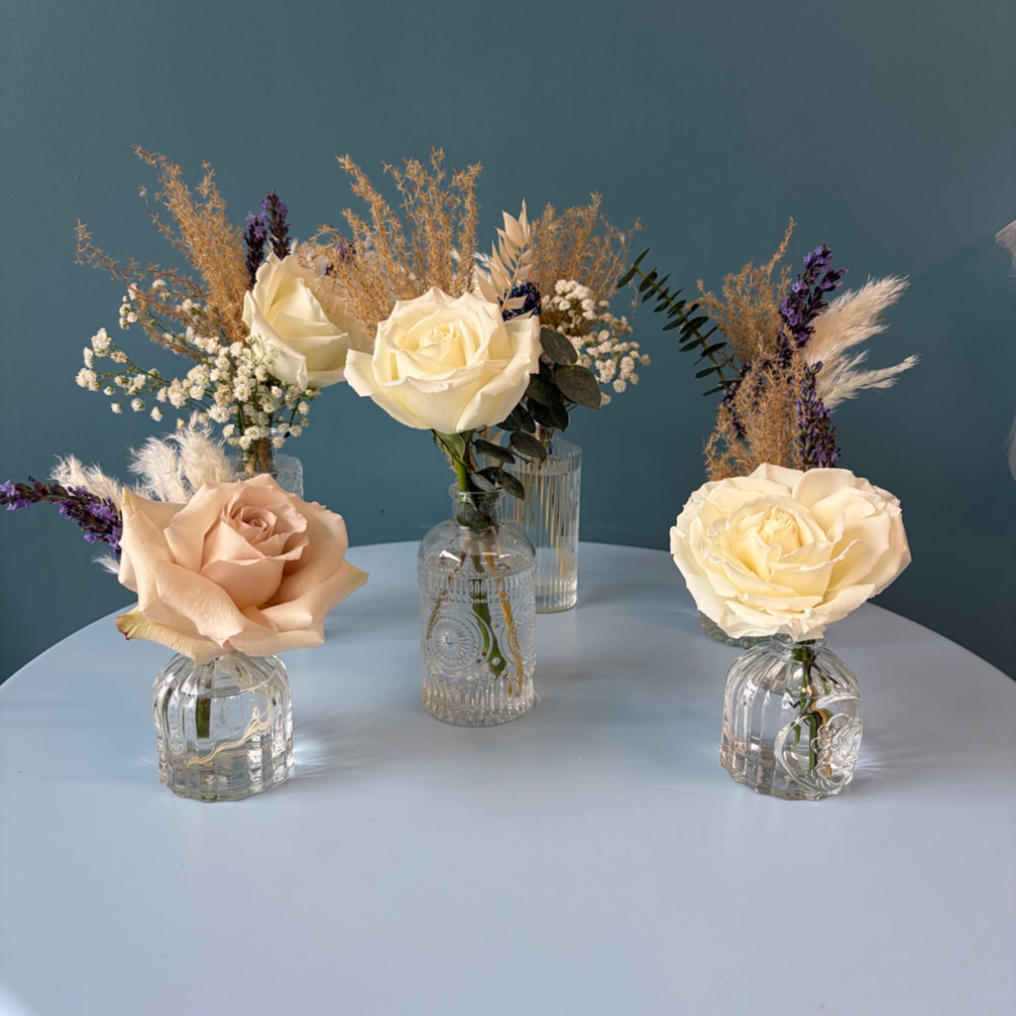Small rose arrangements in clear glass vases on a table