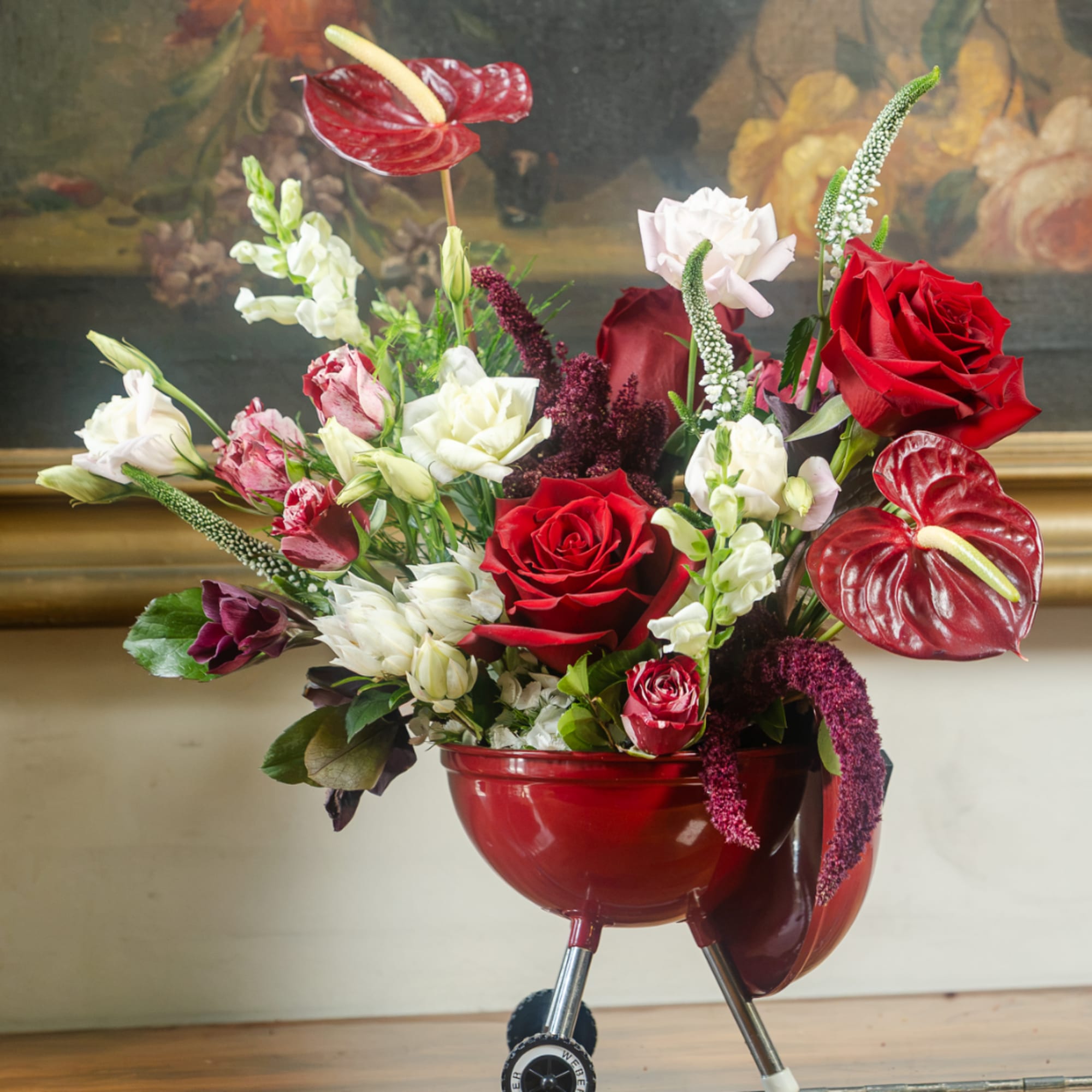 Red and white floral arrangement in a red bowl-shaped vase