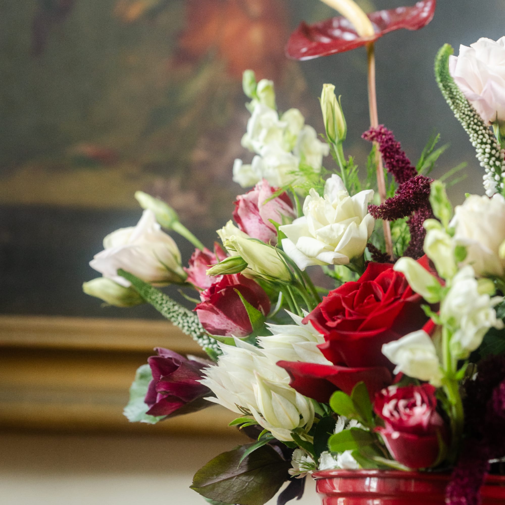 Mixed bouquet of red, white, and pink flowers in a red vase