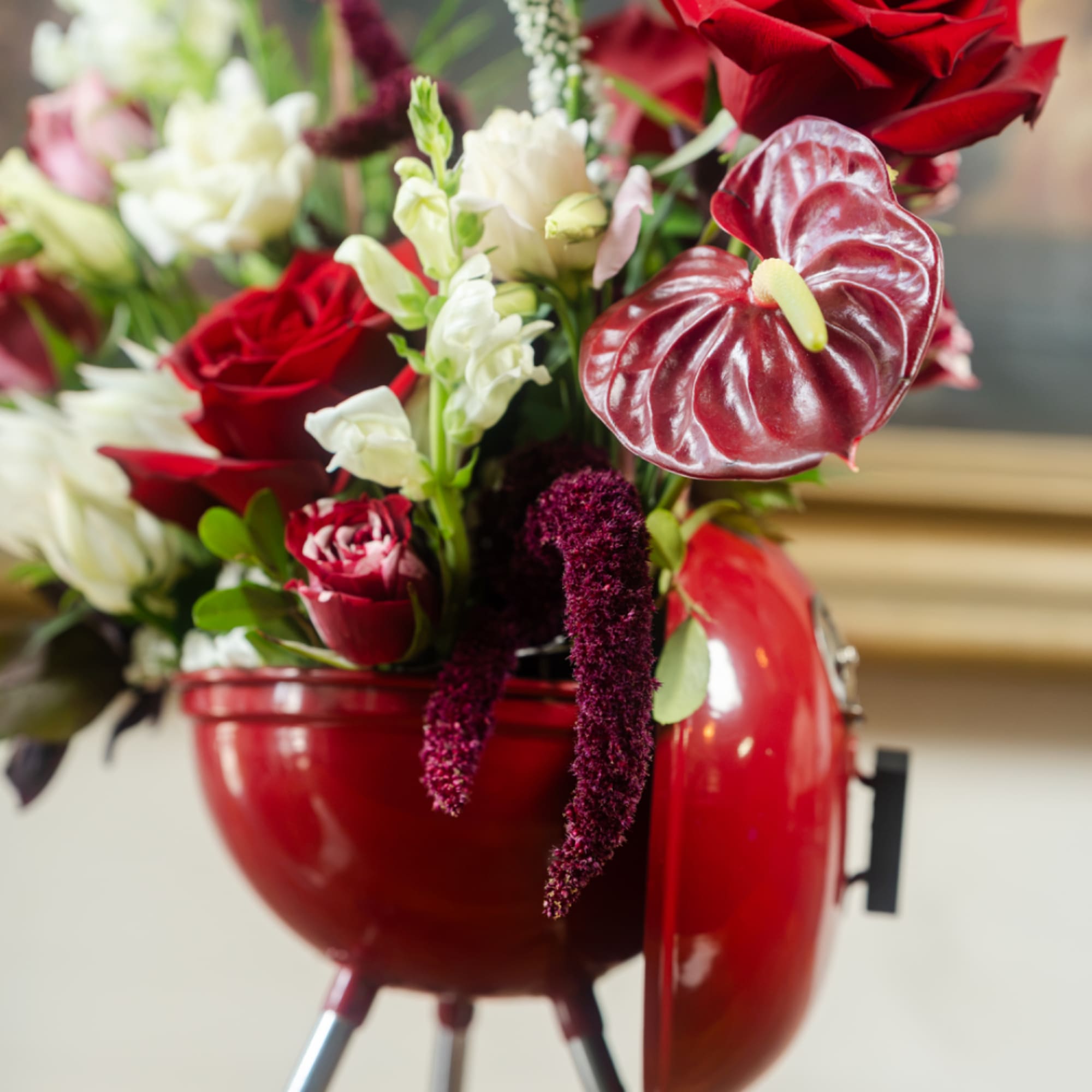 Red and white floral arrangement in a red kettle-style container