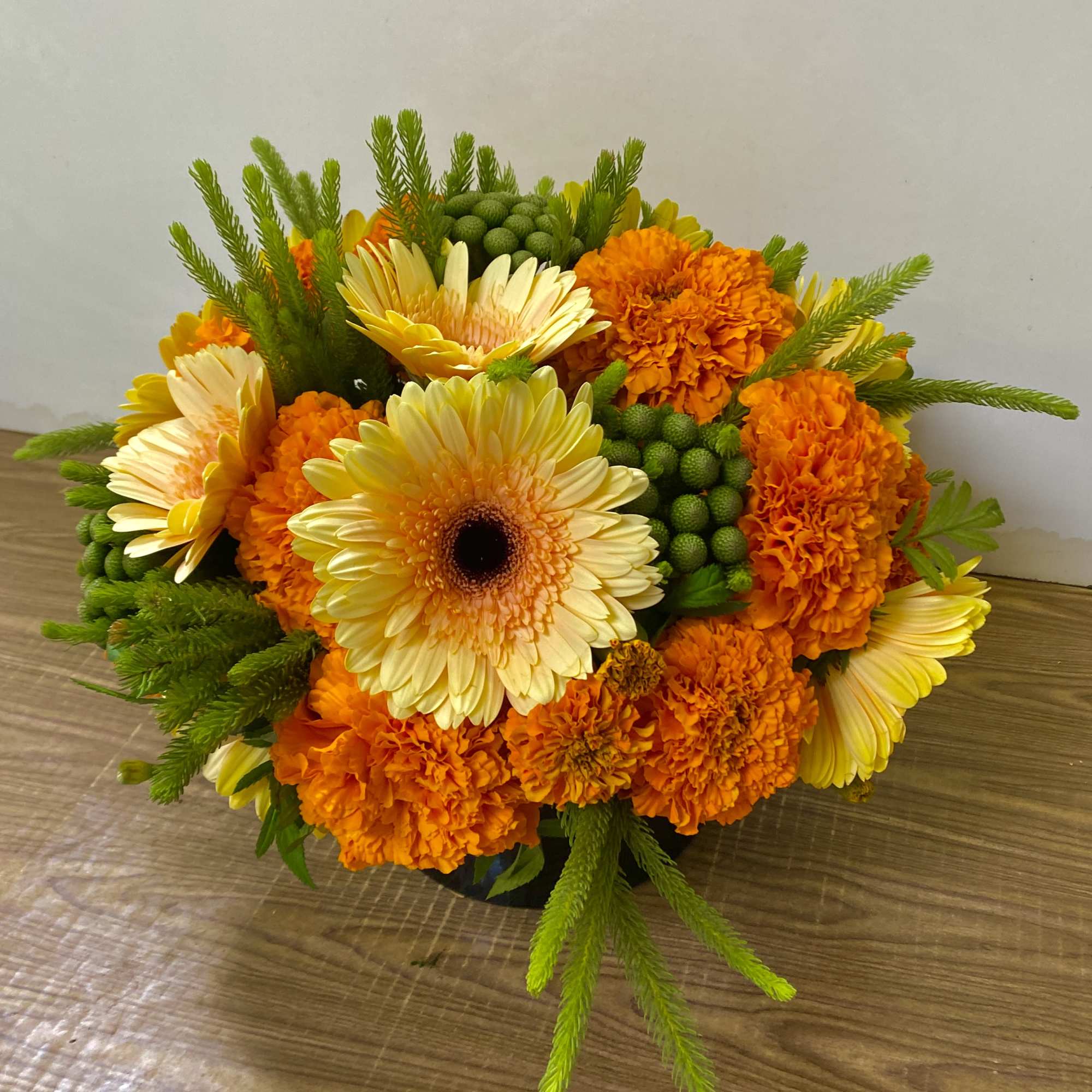Yellow gerbera daisies and orange marigolds in a low arrangement