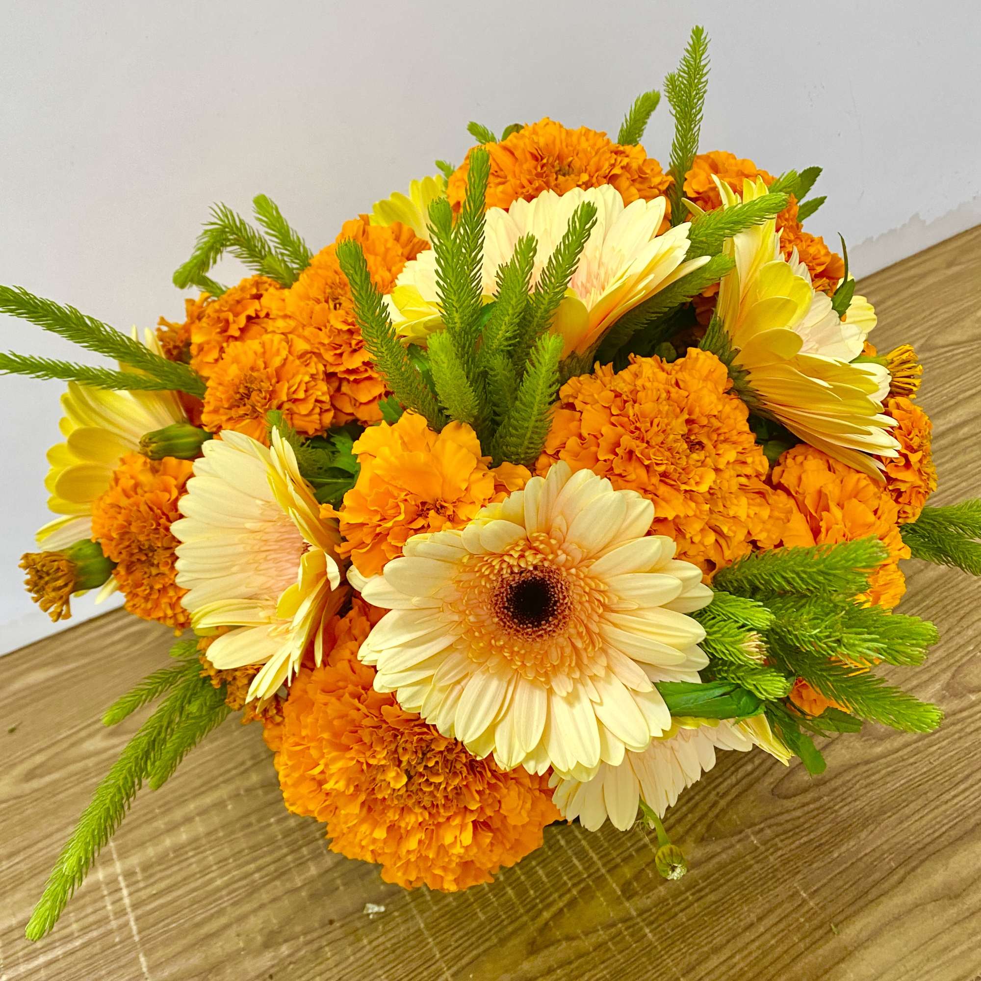 Orange marigolds and pale yellow gerbera daisies in a low bouquet