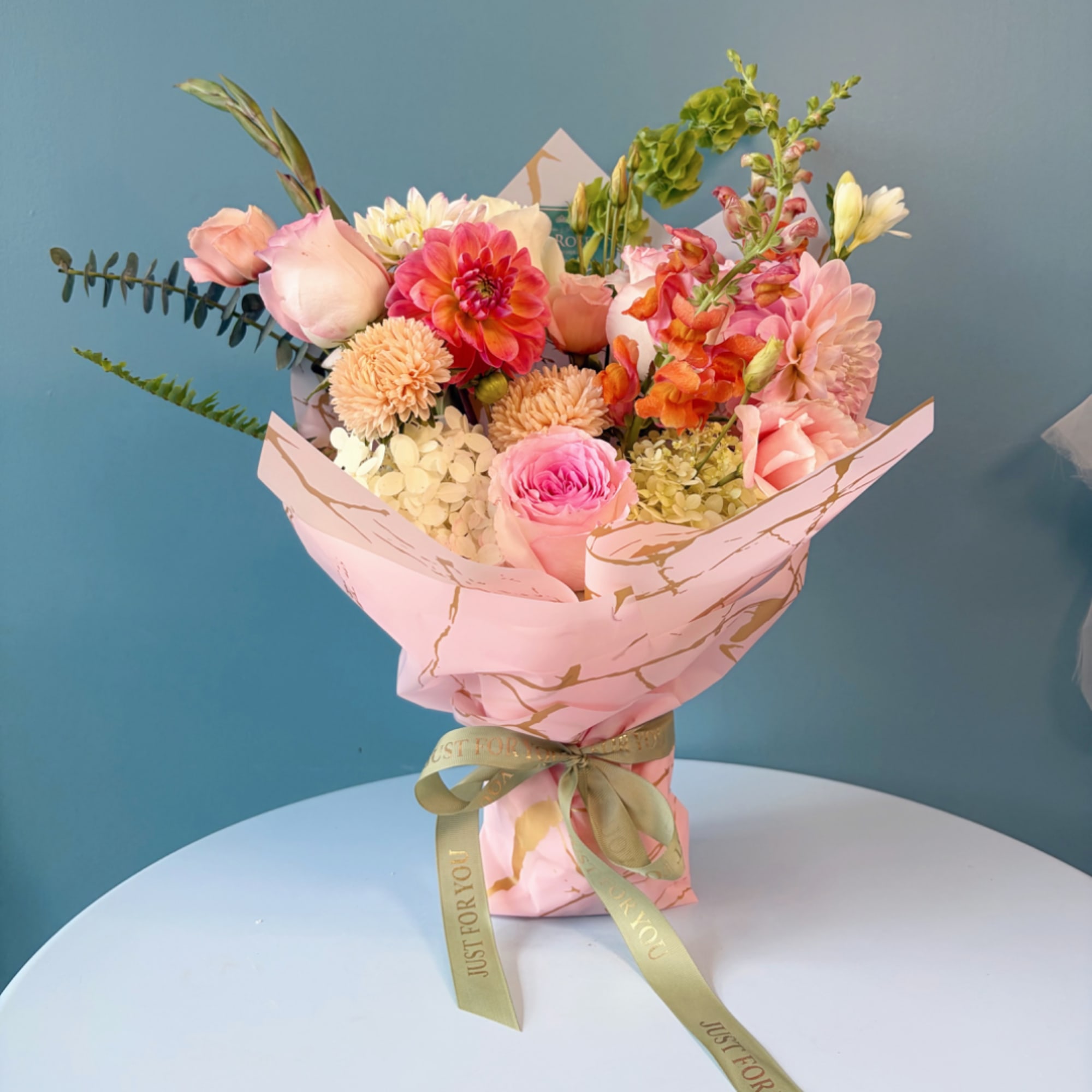 Pink mixed flower bouquet wrapped in pastel paper with a ribbon