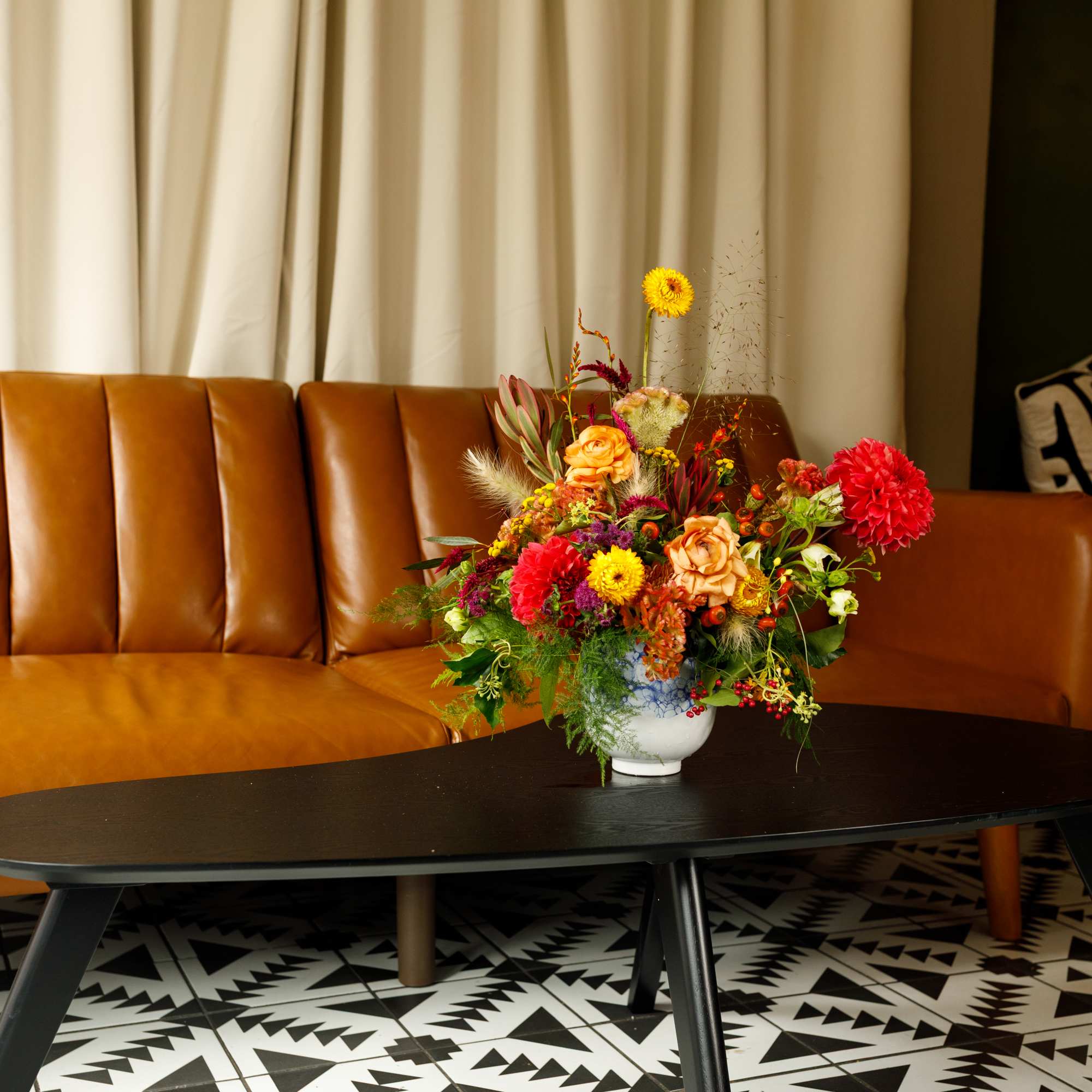 Colorful mixed flower arrangement in a white vase on a coffee table