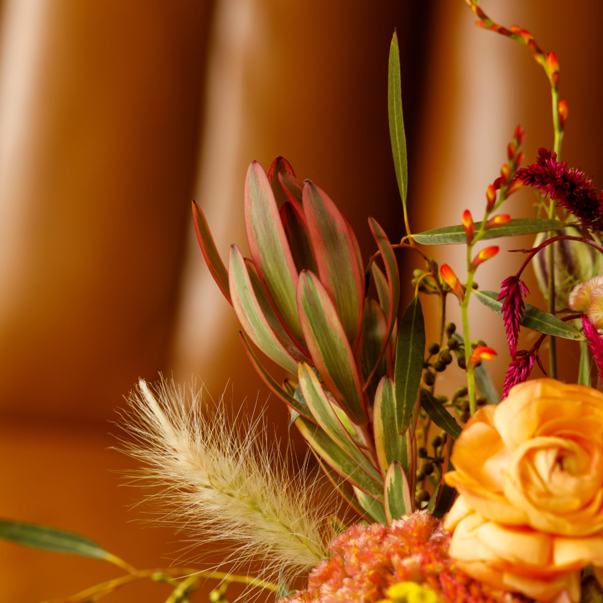 Close-up bouquet with orange roses and mixed textured blooms