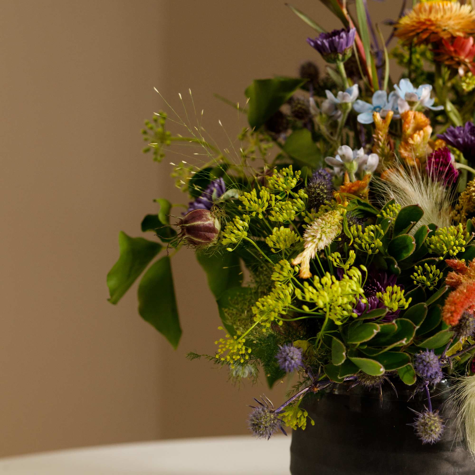 Mixed floral arrangement in a black vase with purple, yellow, and orange blooms
