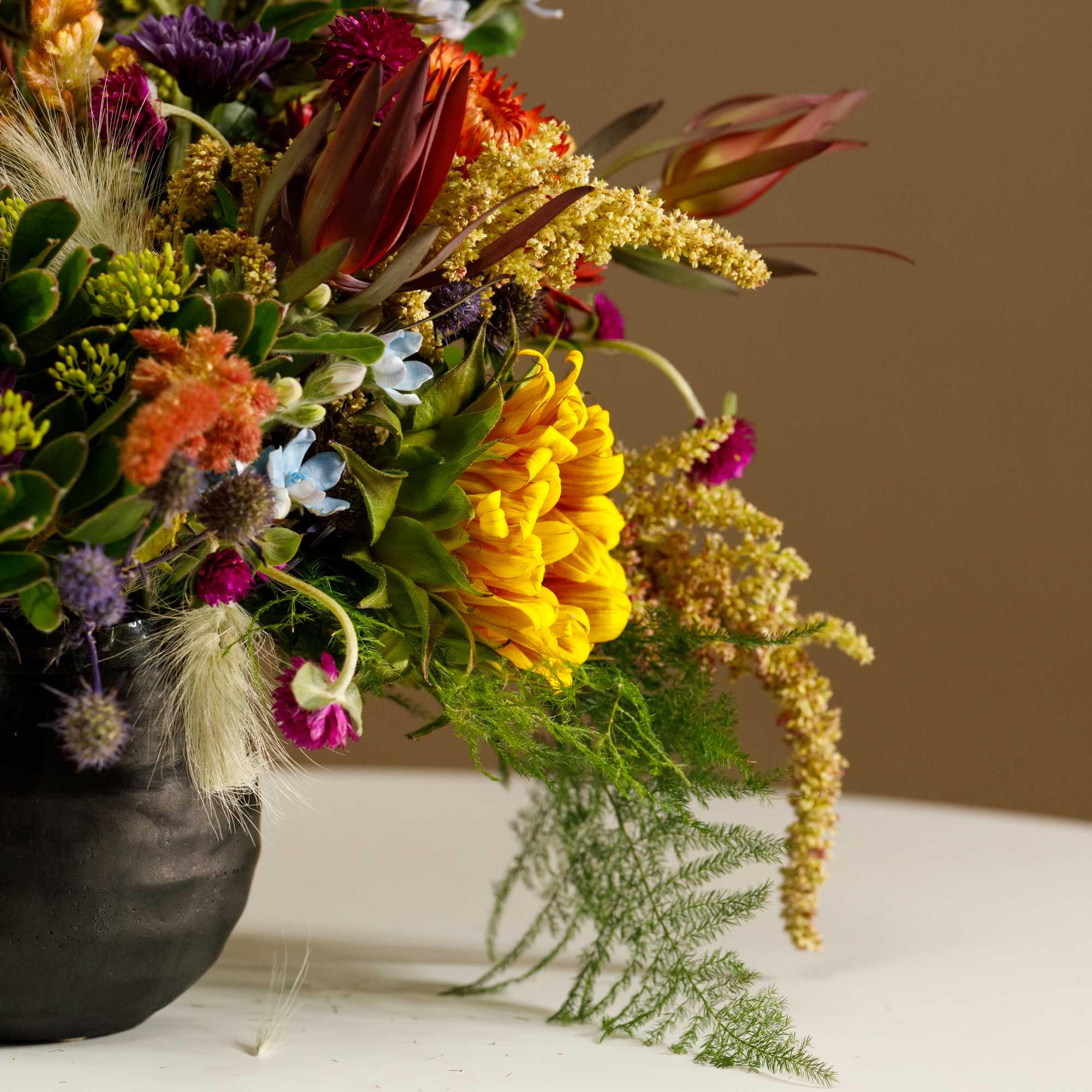 Colorful mixed bouquet in a black vase with yellow and purple blooms