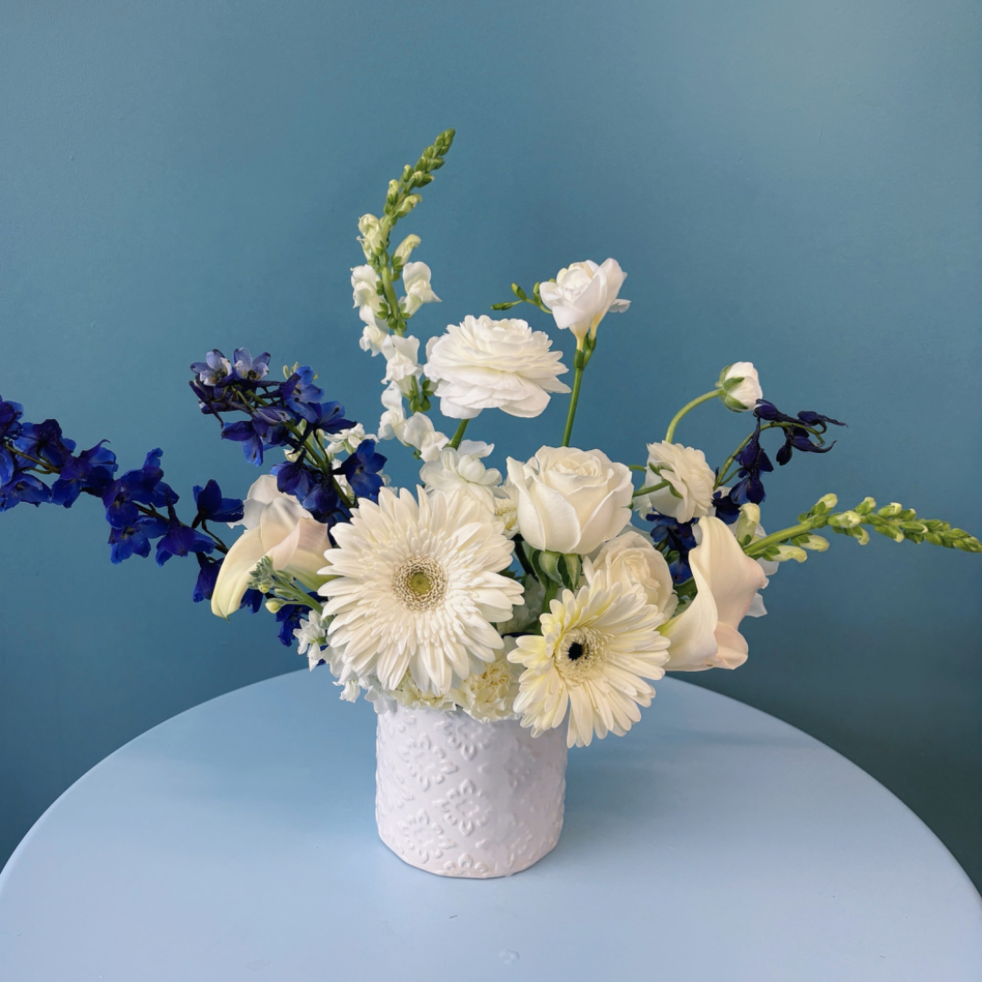 White and blue floral arrangement in a textured white vase