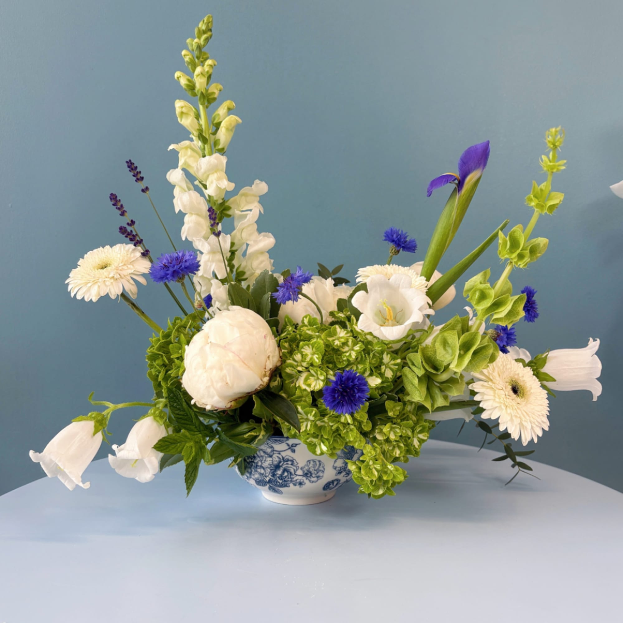 Mixed white and blue flowers arranged in a blue-and-white ceramic bowl