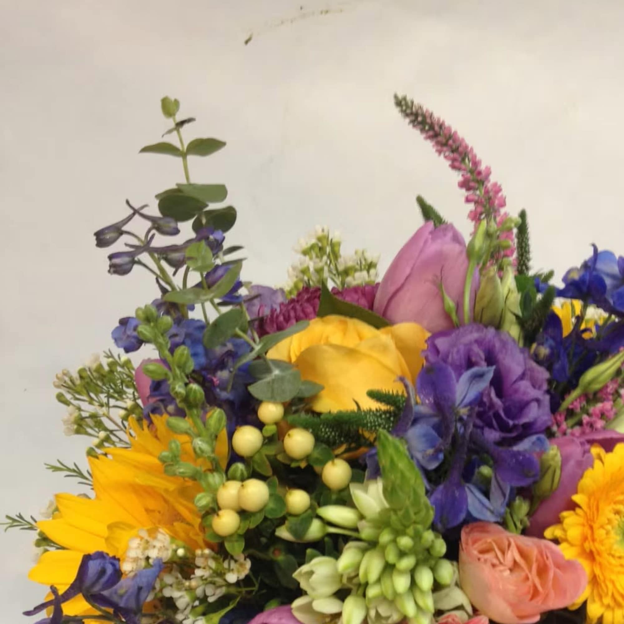 Colorful mixed bouquet with yellow sunflowers, purple blooms, and pink roses