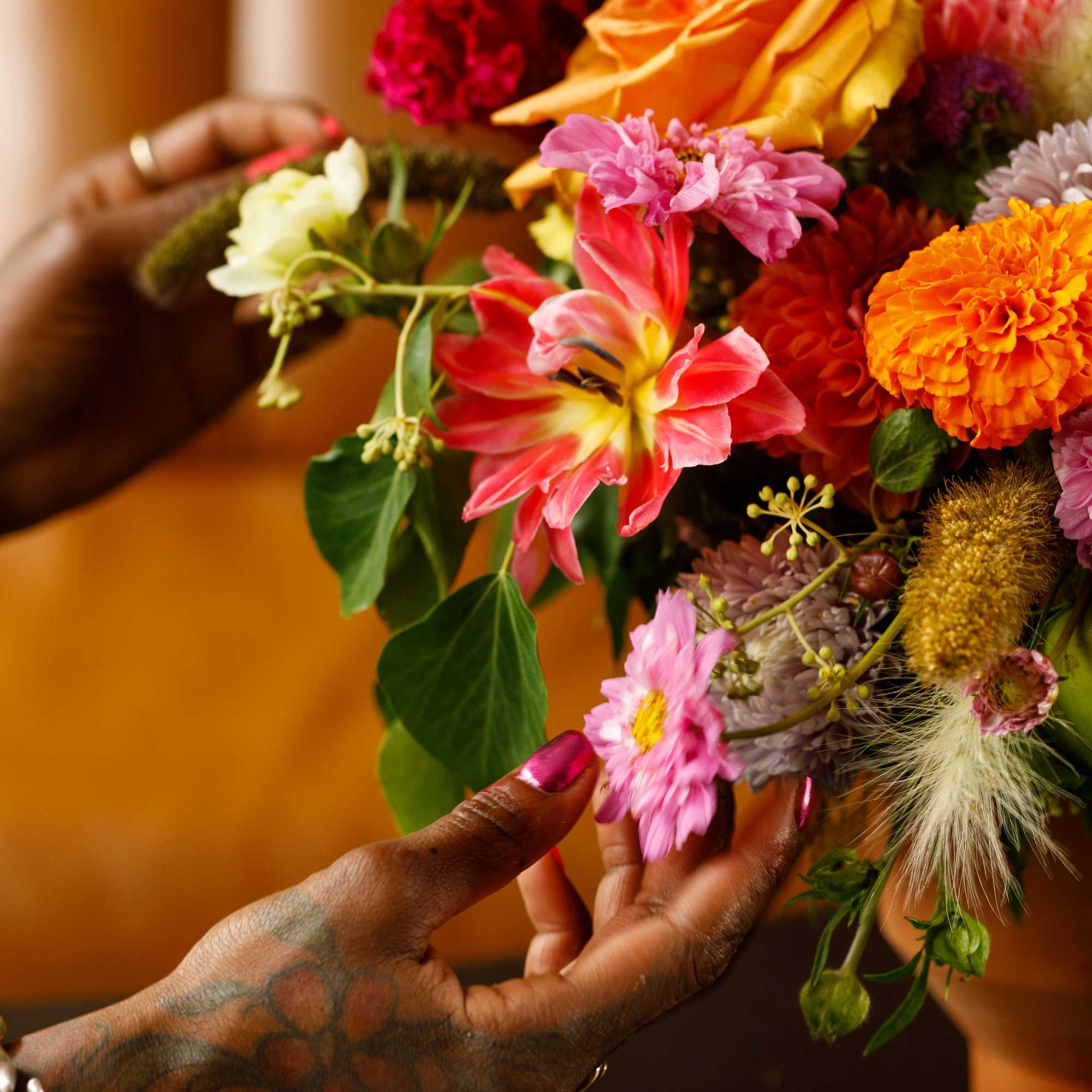 Hands holding a colorful mixed bouquet with roses and daisies