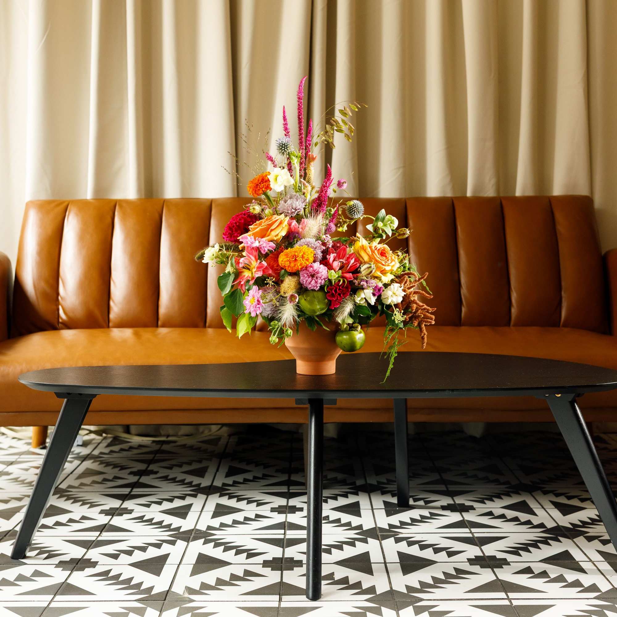 Colorful mixed flower arrangement in a terracotta vase on a coffee table