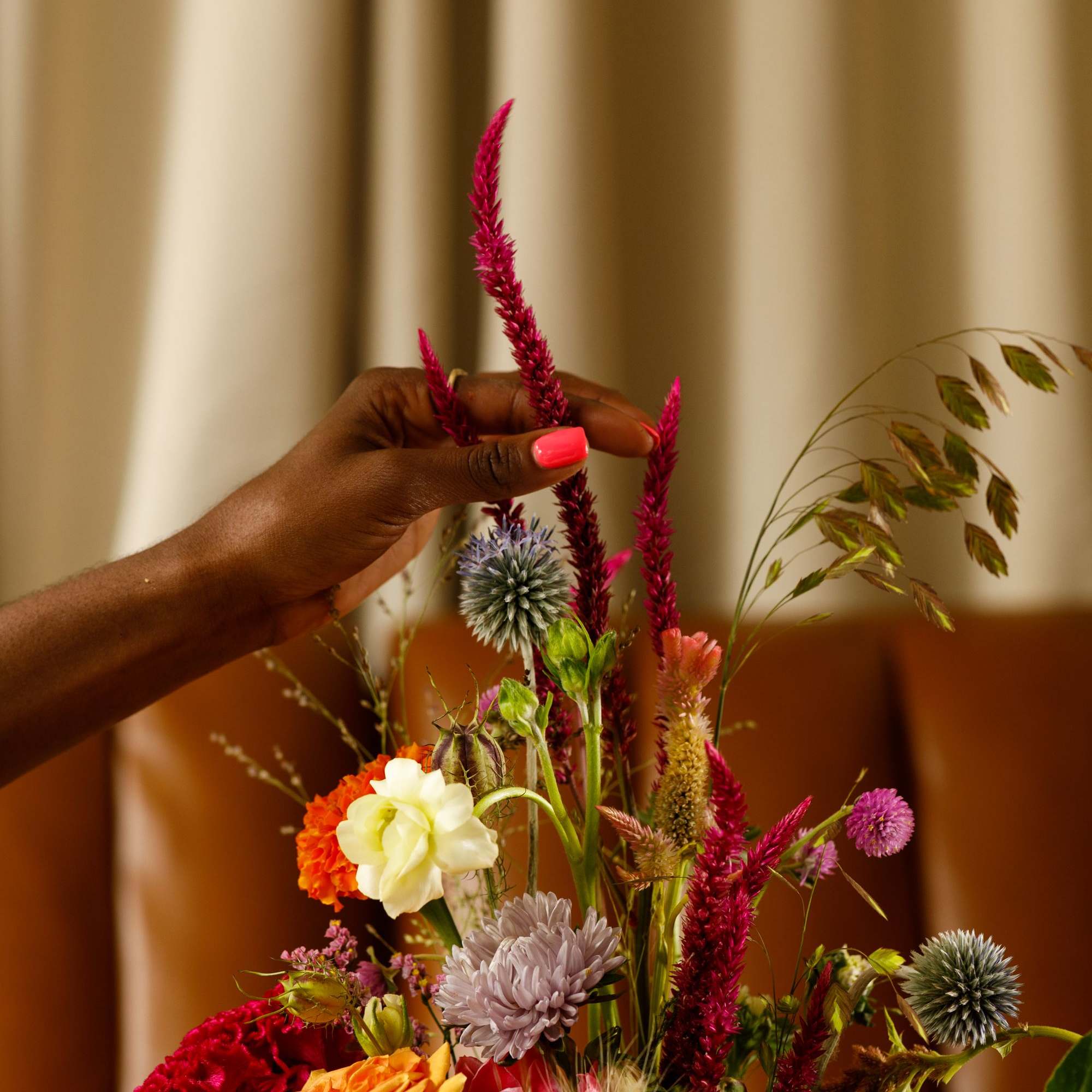 Hand arranging a colorful mixed bouquet with roses and assorted blooms