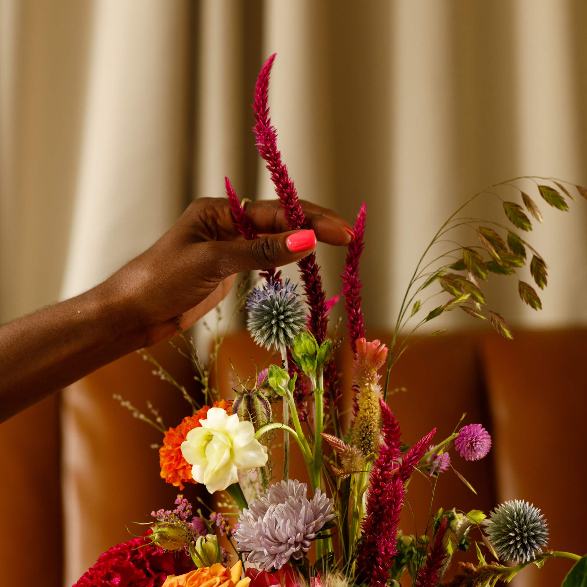 Hand arranging a colorful mixed bouquet with tall magenta spikes