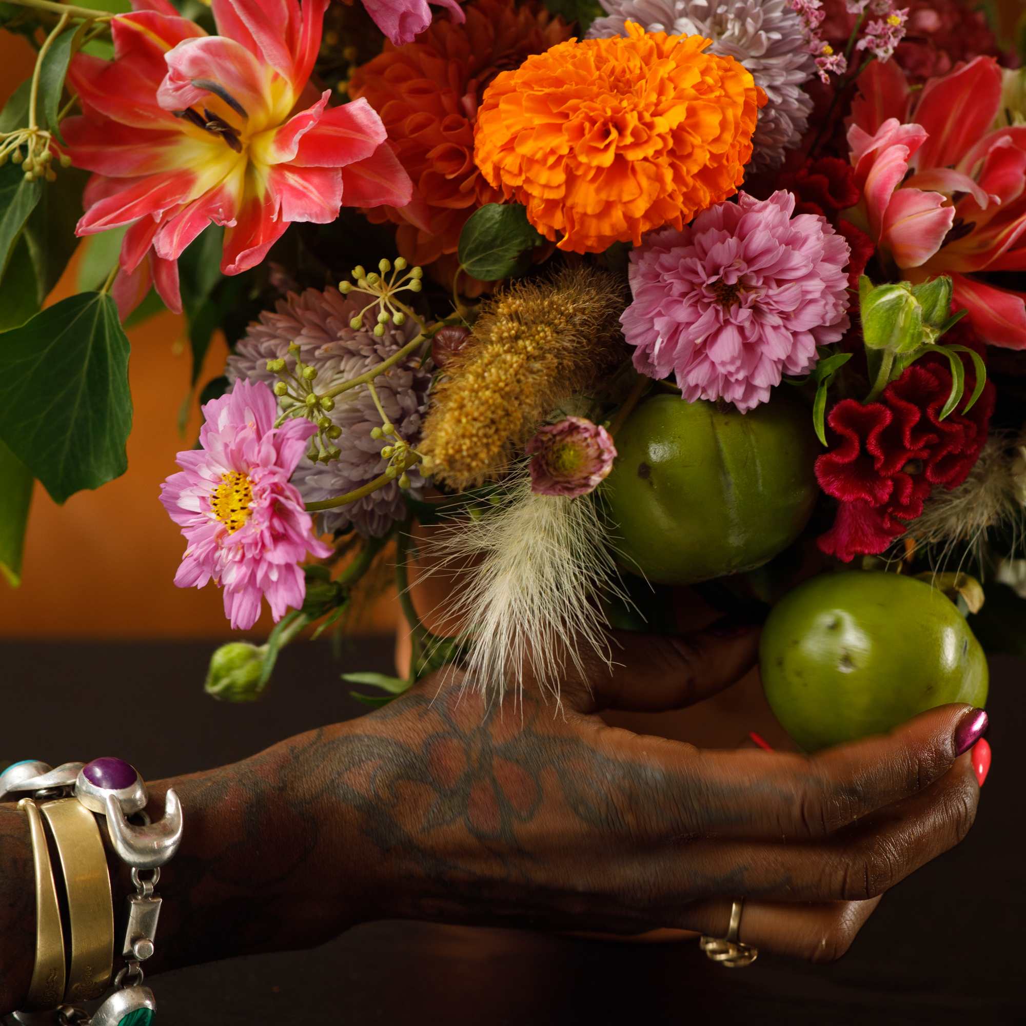 Colorful bouquet with tulips, chrysanthemums, and marigolds held in a hand