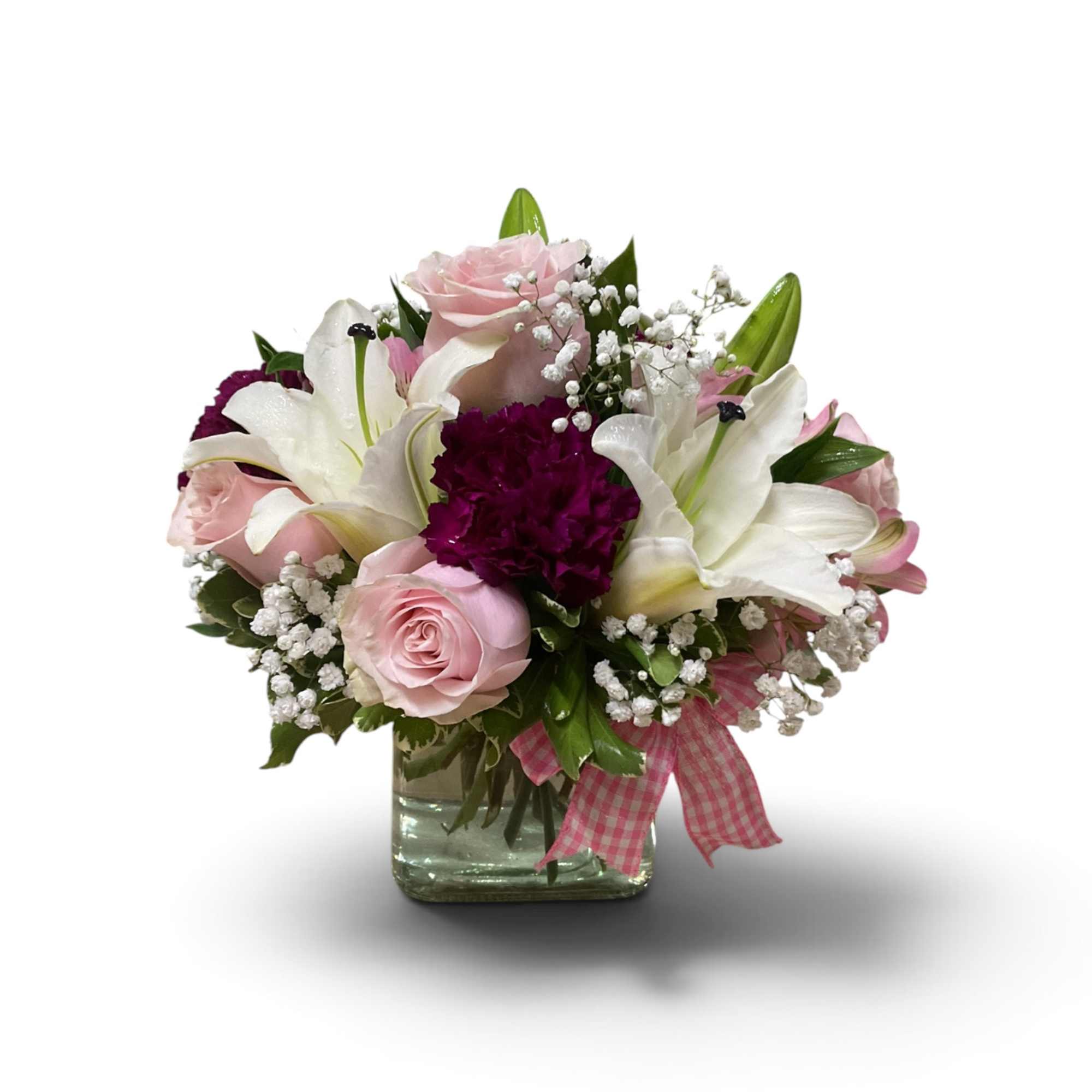 Pink roses and white lilies in a glass vase with a pink ribbon