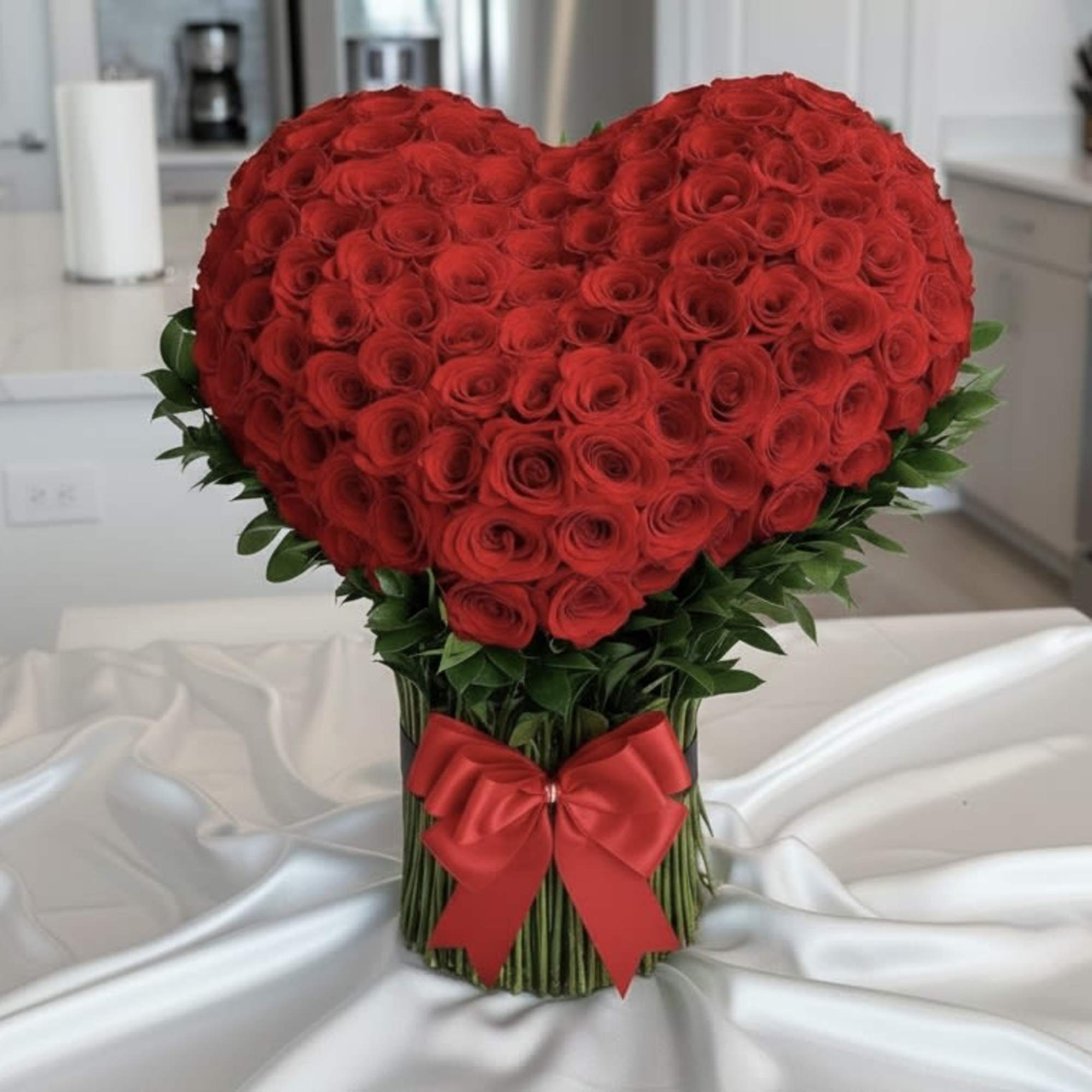 Heart-shaped bouquet of red roses with a red ribbon