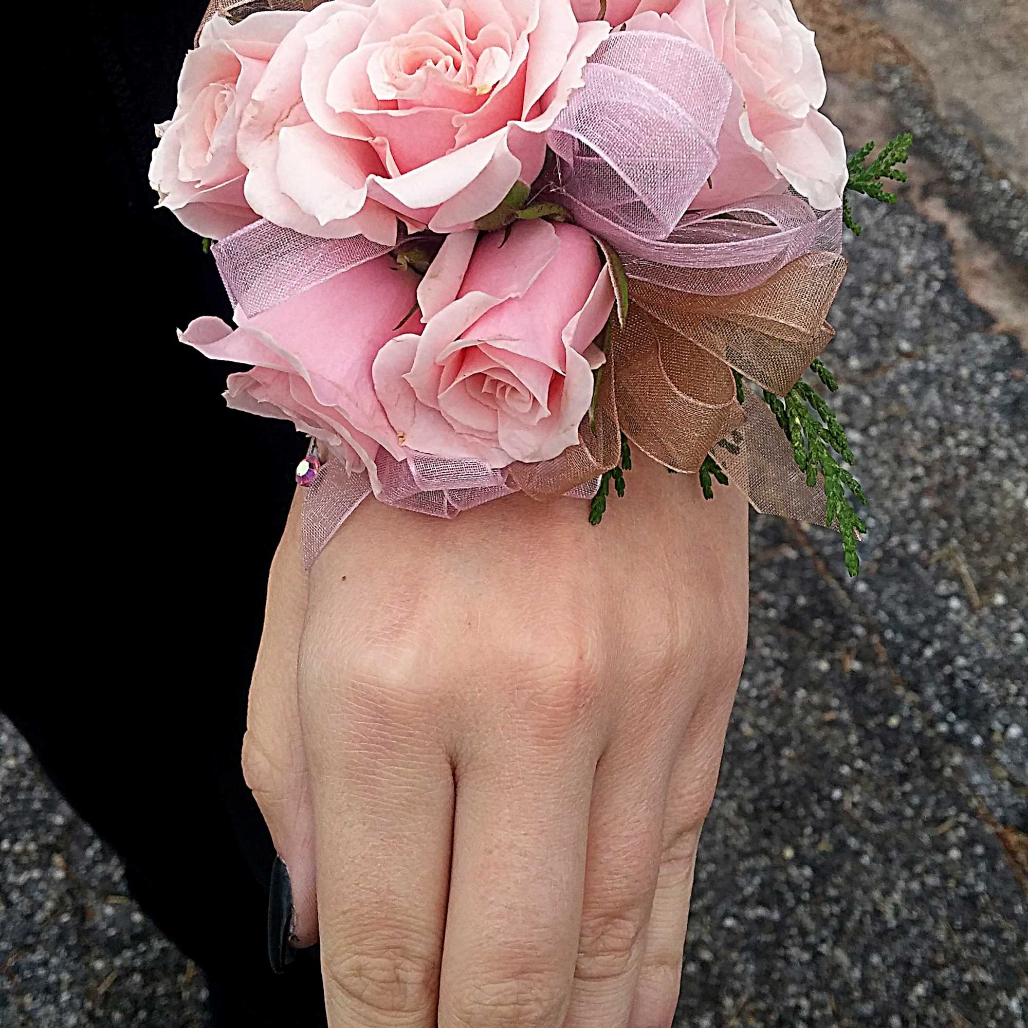 Pink rose wrist corsage with ribbon on a hand