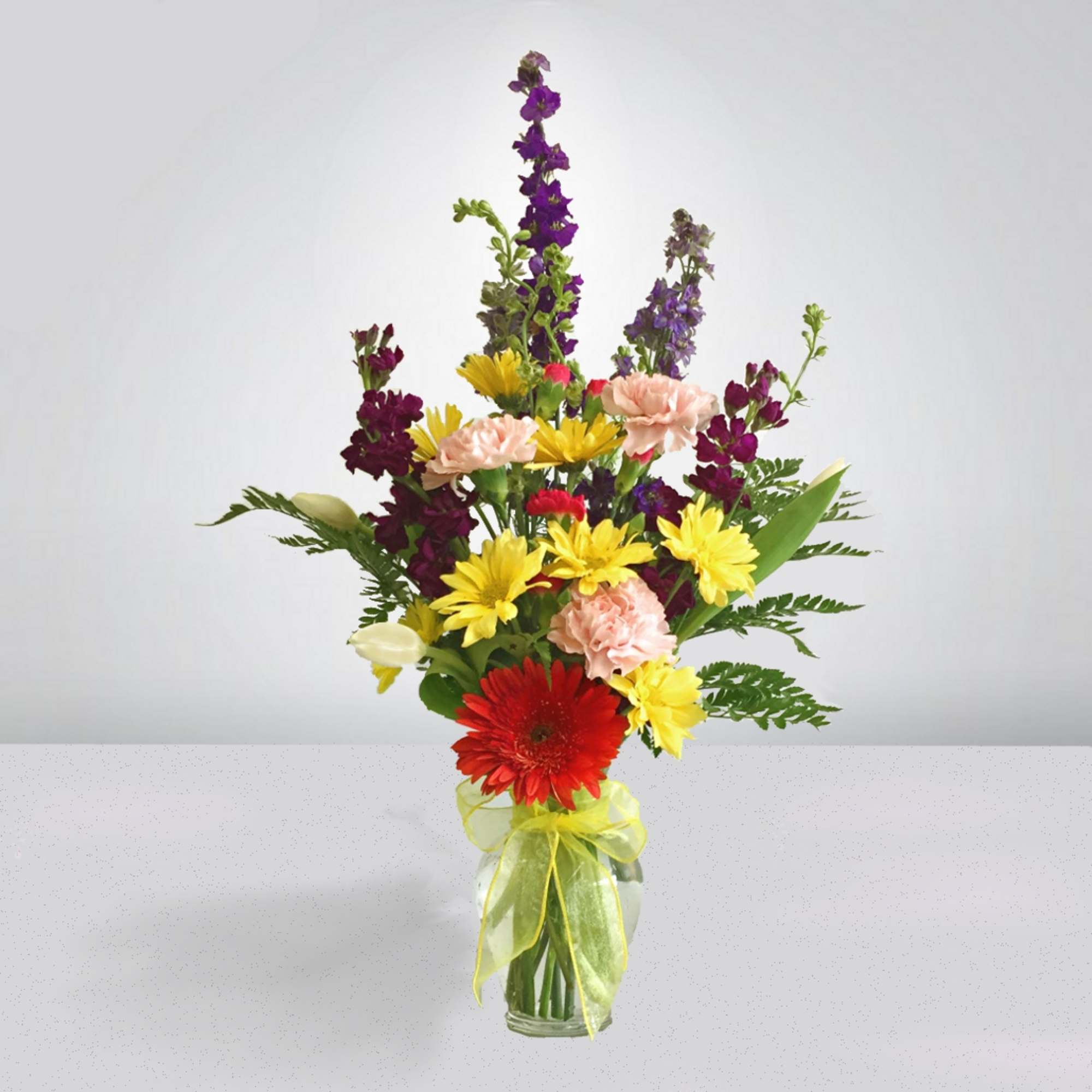 Mixed bouquet in a glass vase with red, yellow, pink, and purple flowers