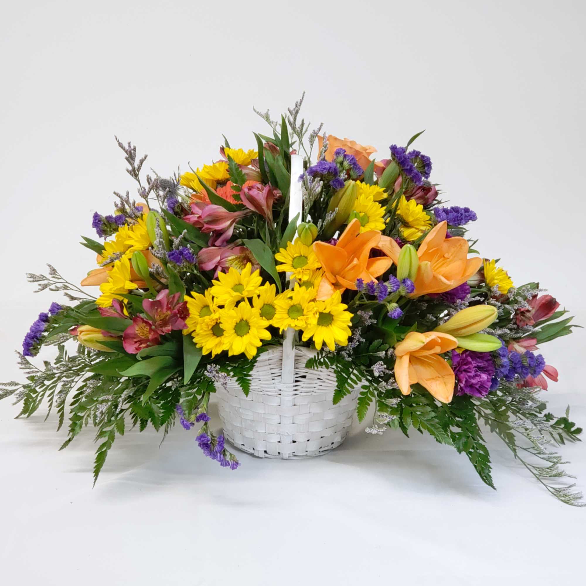 Mixed bouquet in a white basket with yellow daisies and orange lilies