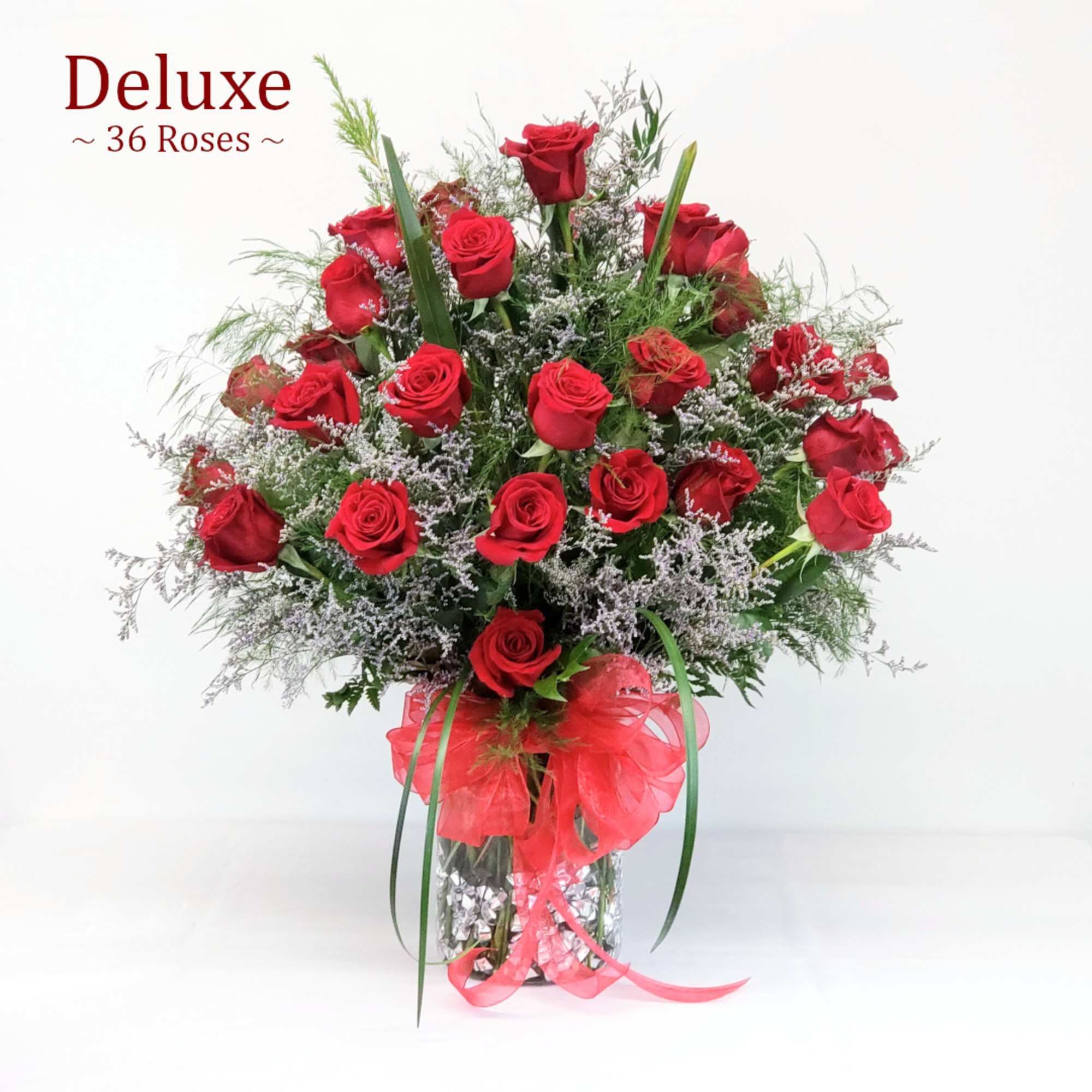 Red roses arranged in a clear vase with a red ribbon bow