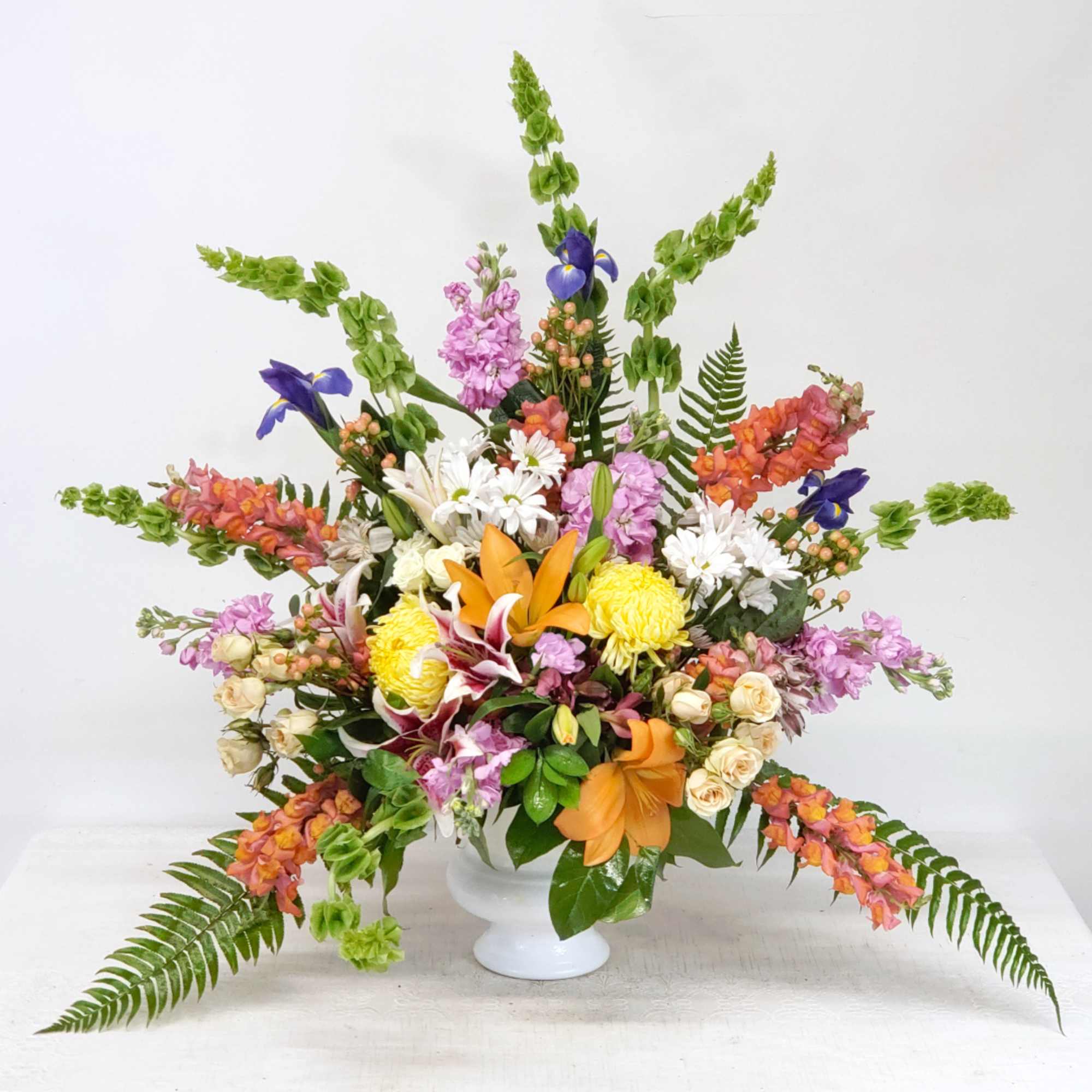 Colorful mixed flower arrangement in a white pedestal vase