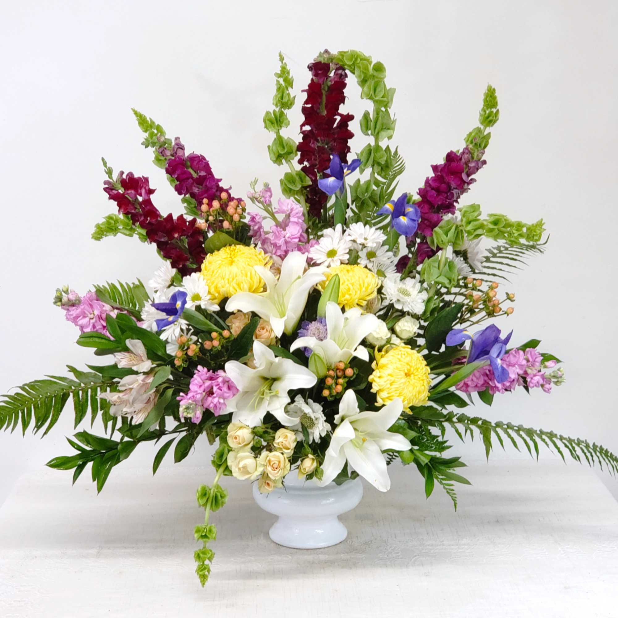 Mixed bouquet in a white vase with lilies, roses, and colorful blooms