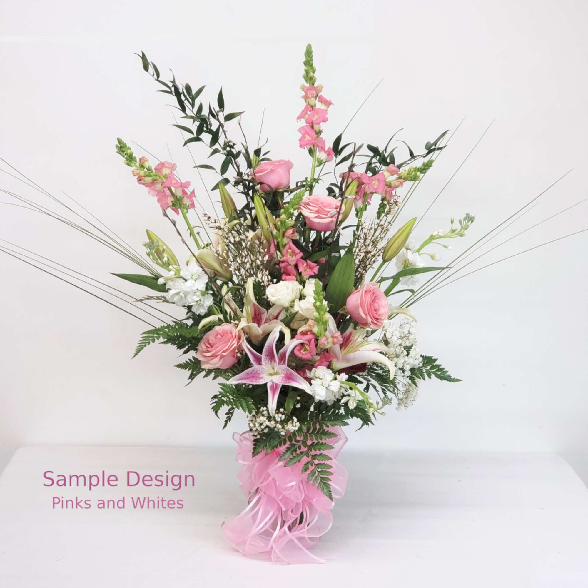 Tall pink and white floral arrangement with a pink ribbon bow