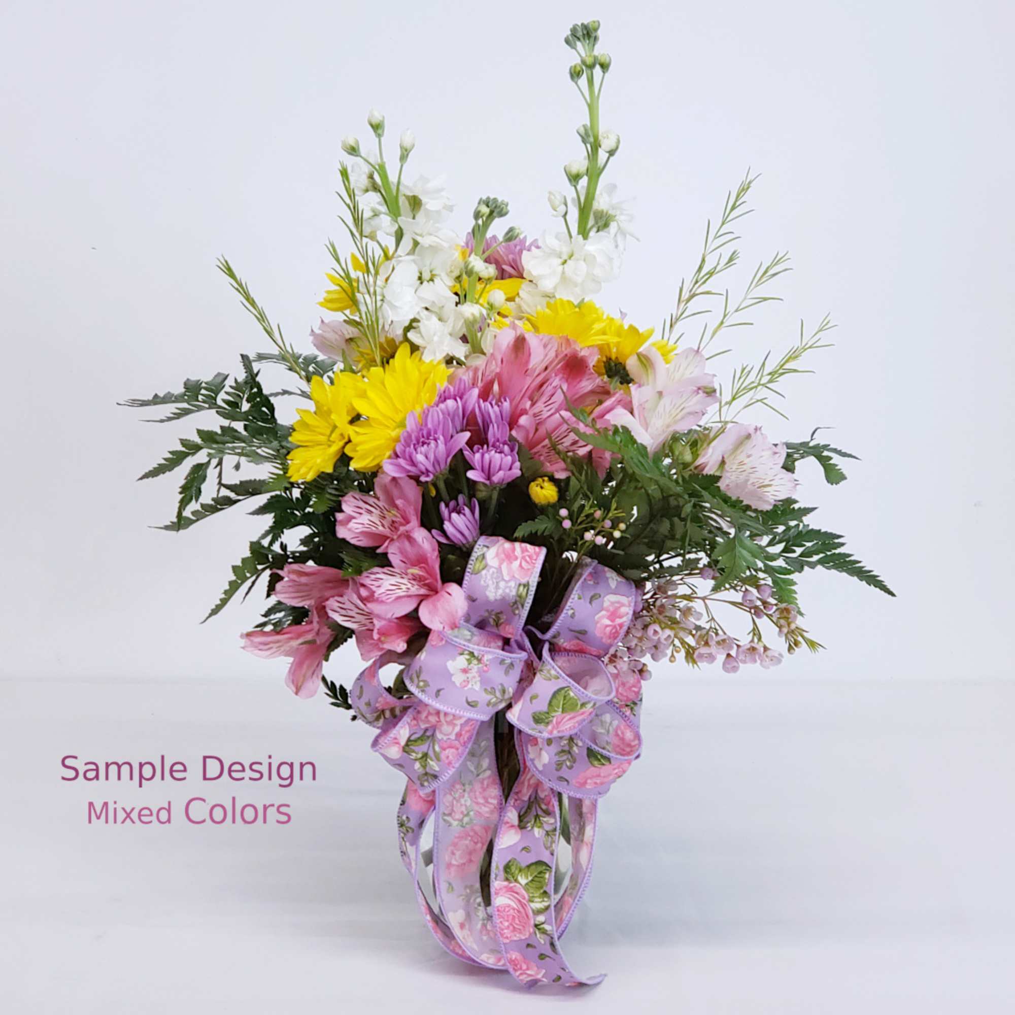 Mixed bouquet of pink, yellow, and white flowers with a lavender ribbon