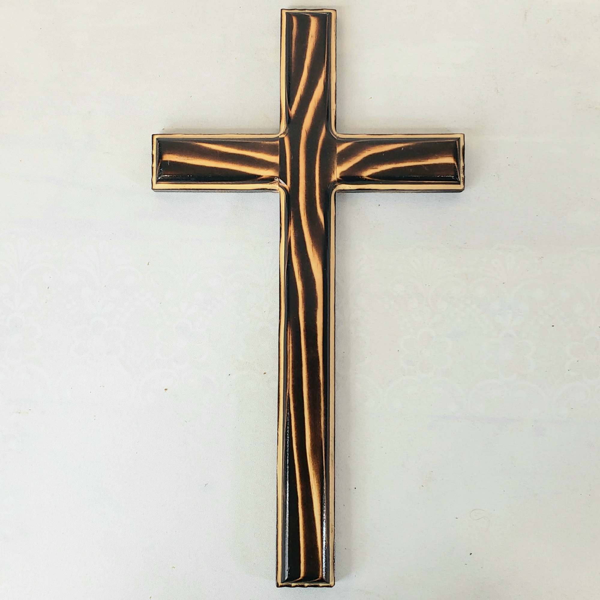A decorative cross with a black and gold striped finish