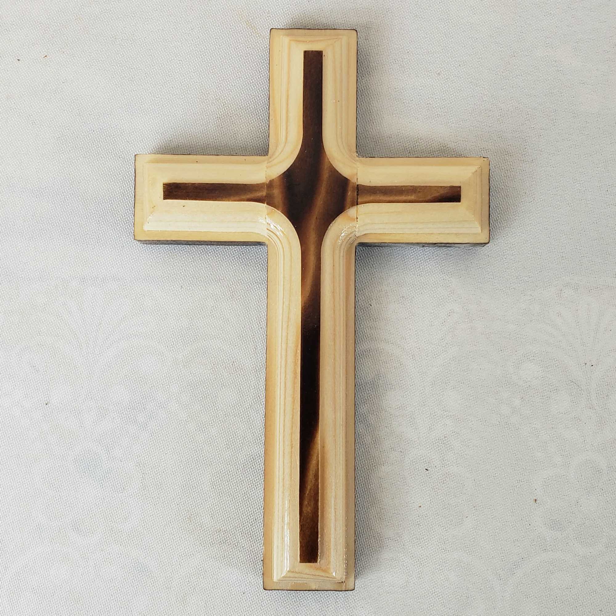 Wooden cross on a light fabric background