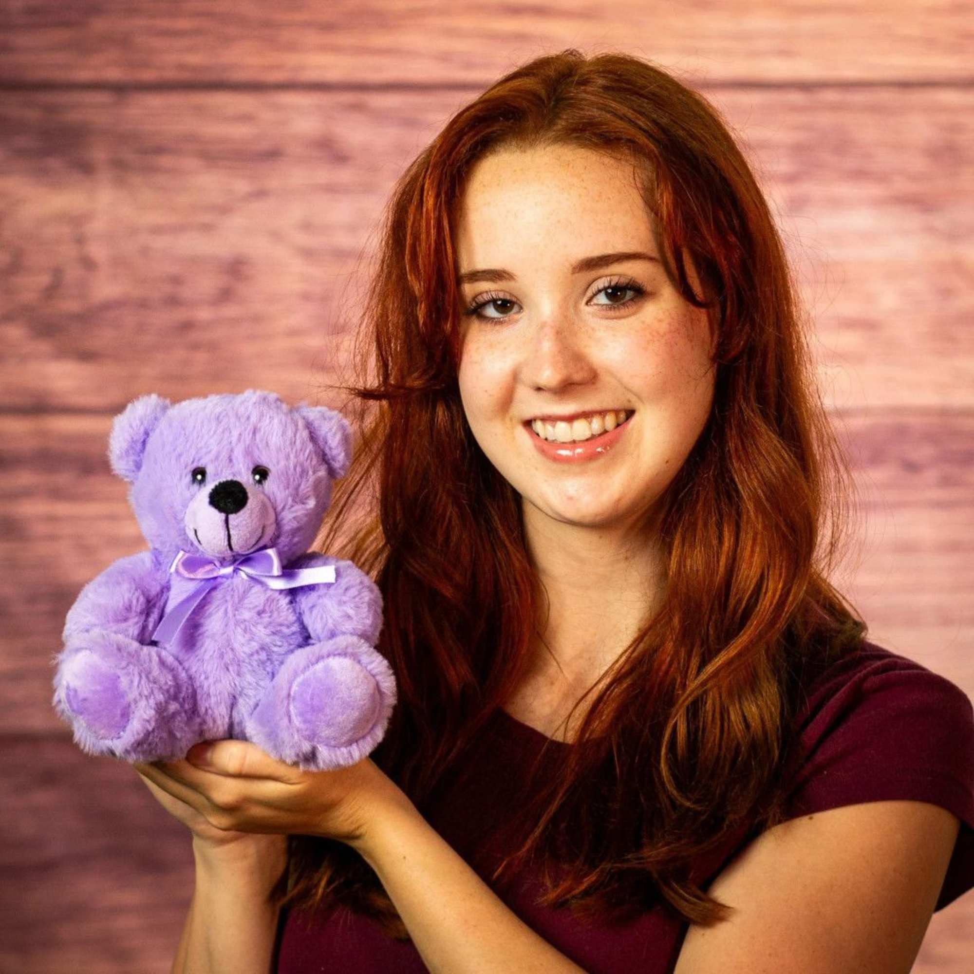 Woman holding a purple teddy bear with a ribbon