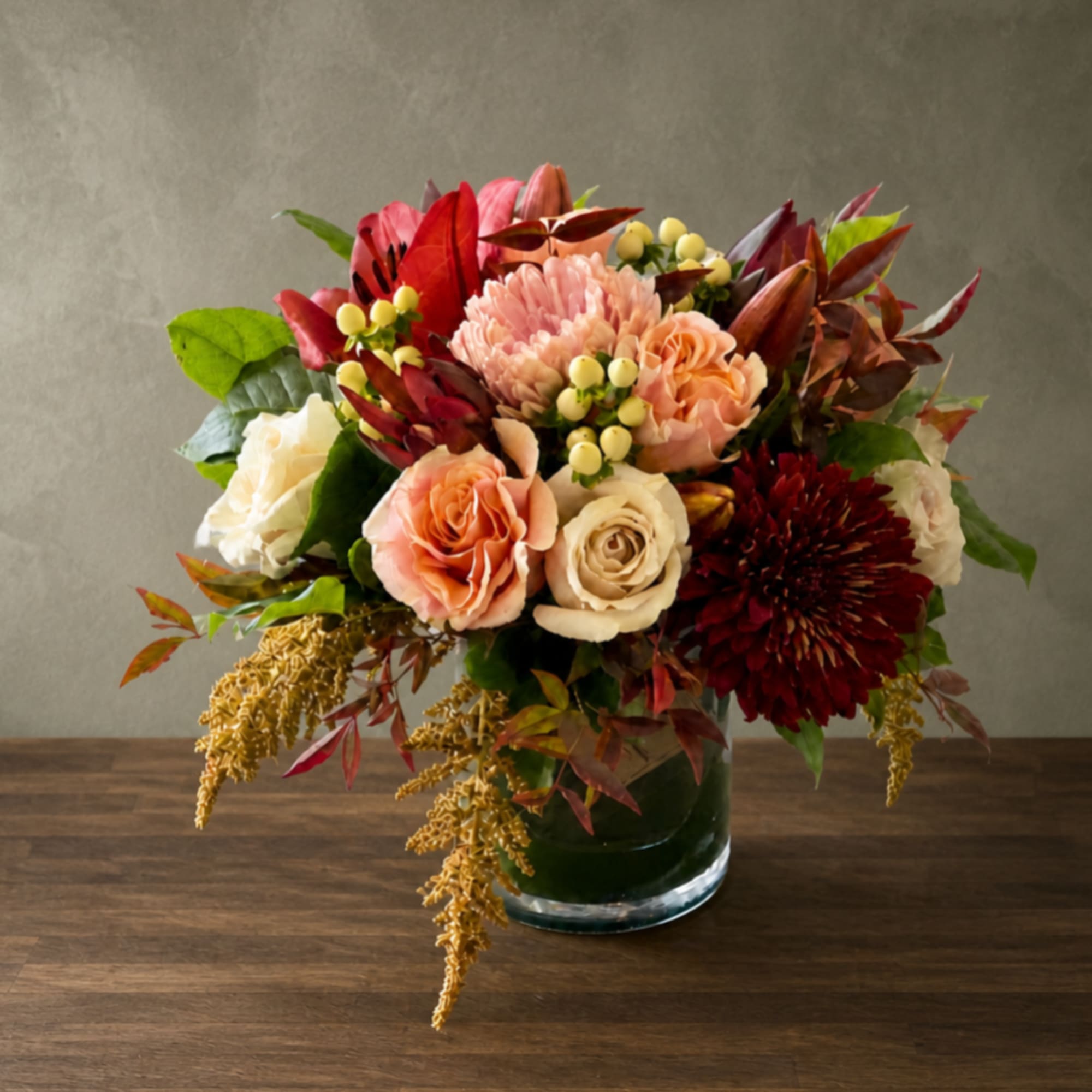 Mixed bouquet of roses, chrysanthemums, and lilies in a glass vase
