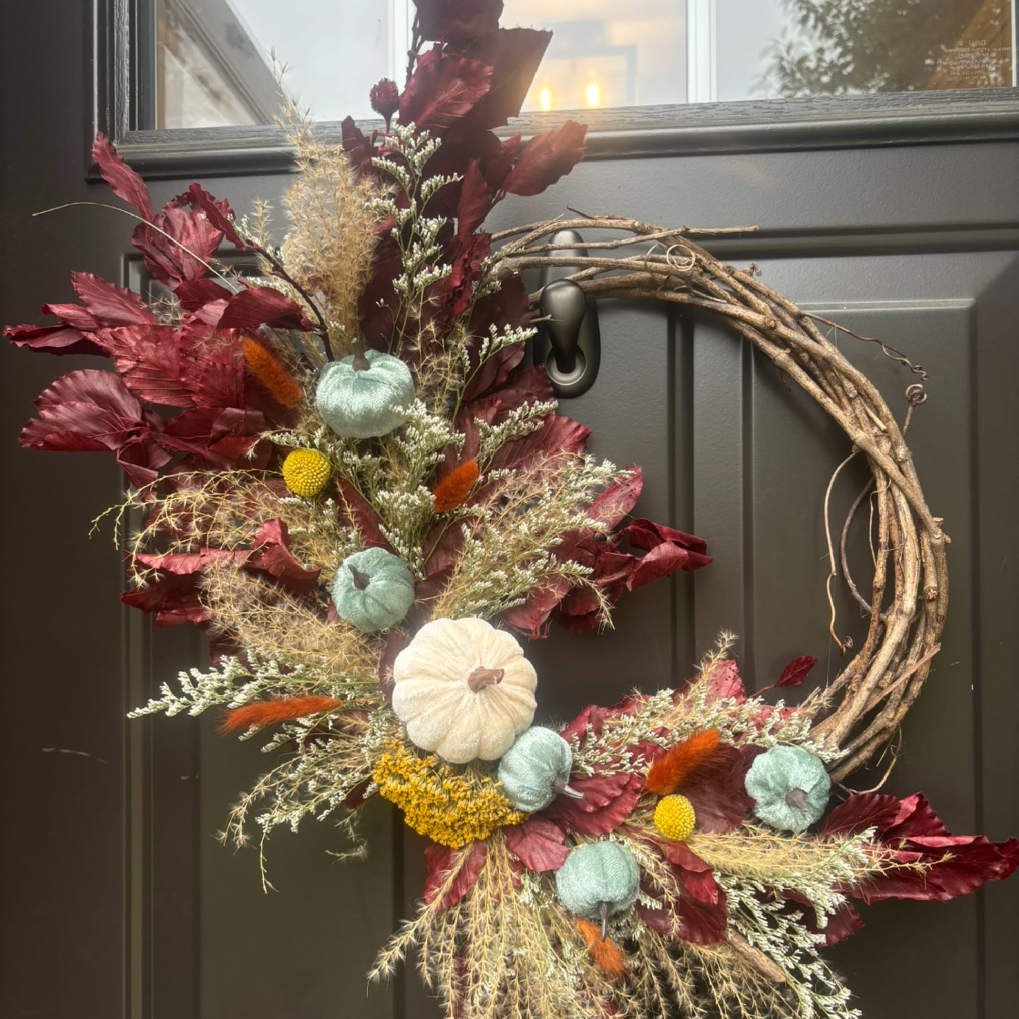Autumn wreath with dried foliage, small pumpkins, and a grapevine base