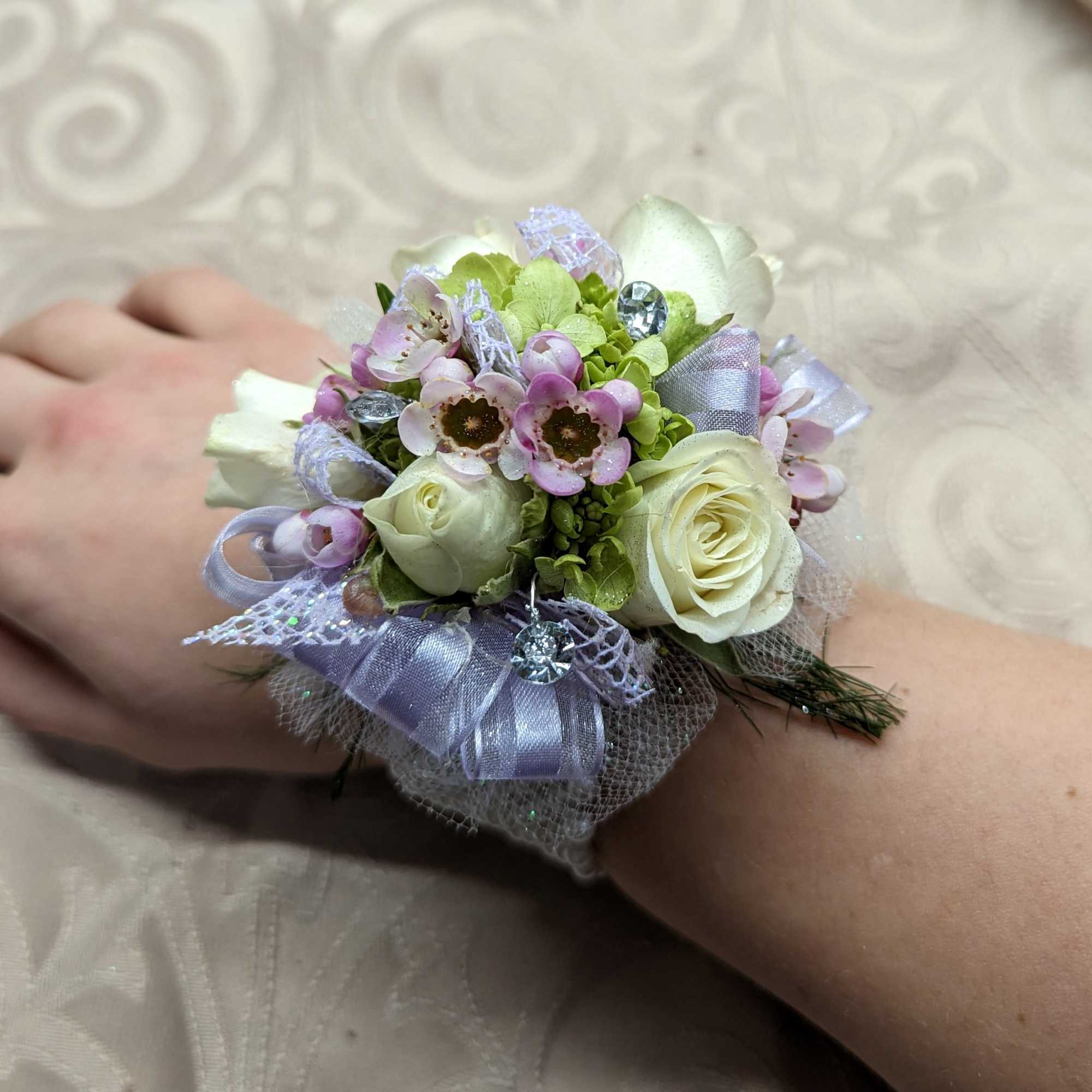 Floral wrist corsage with white roses and small pink blossoms