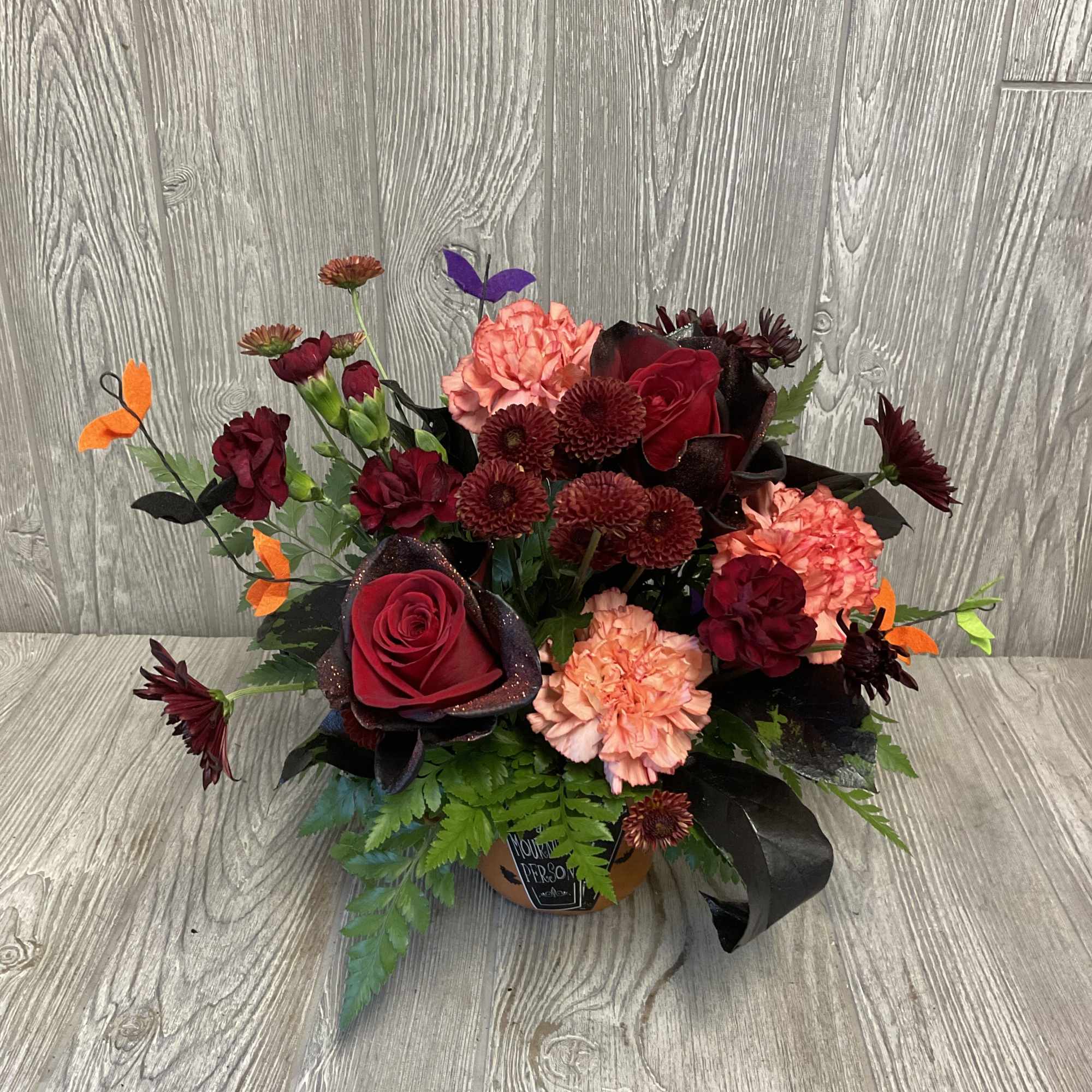 Mixed bouquet of red and peach flowers in a small container