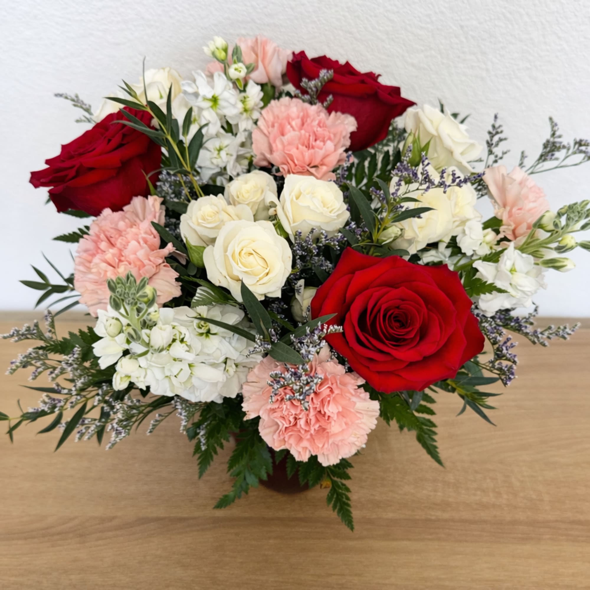 Bouquet of red and white roses with pink carnations in a vase