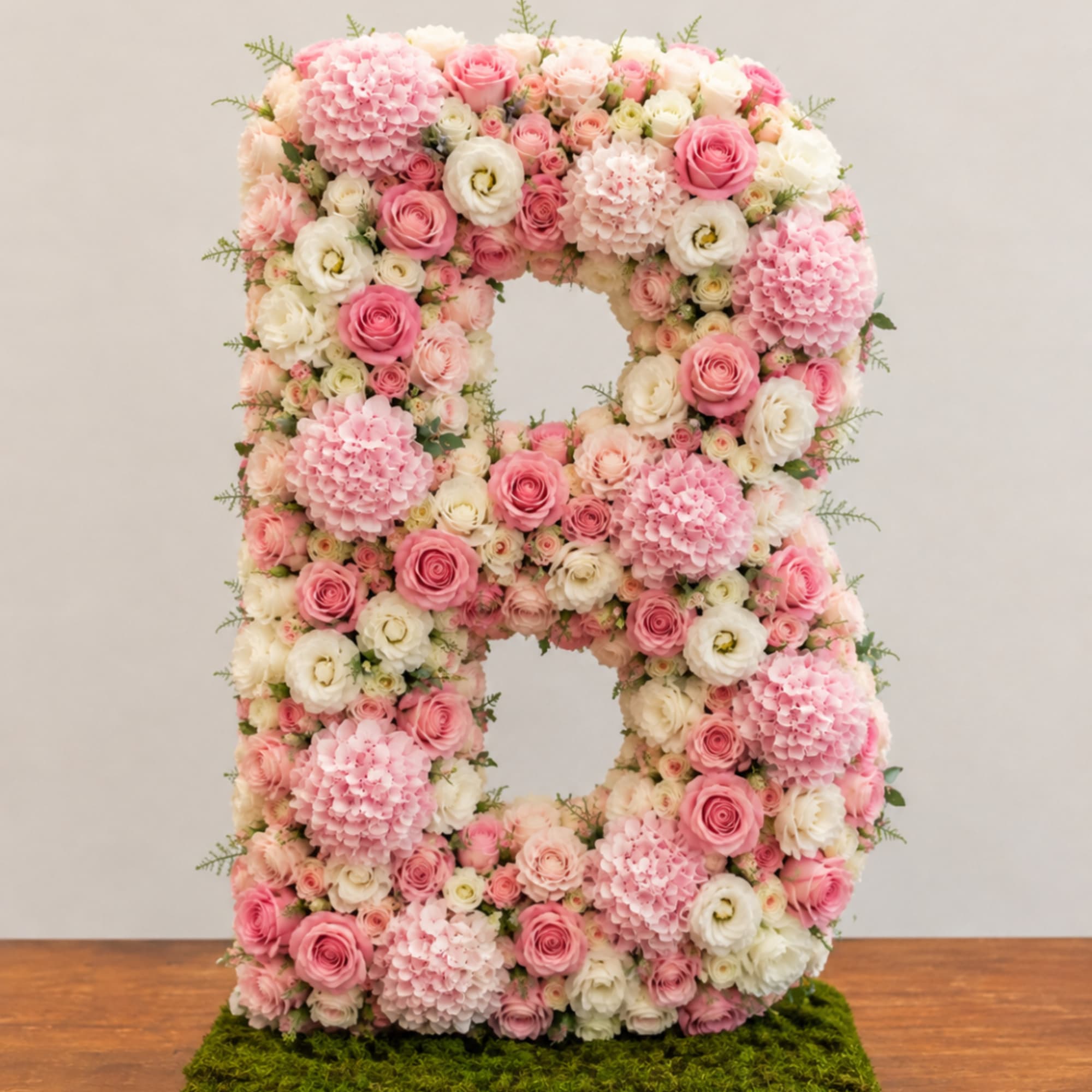 Large floral number 8 made of pink and white flowers on a moss base