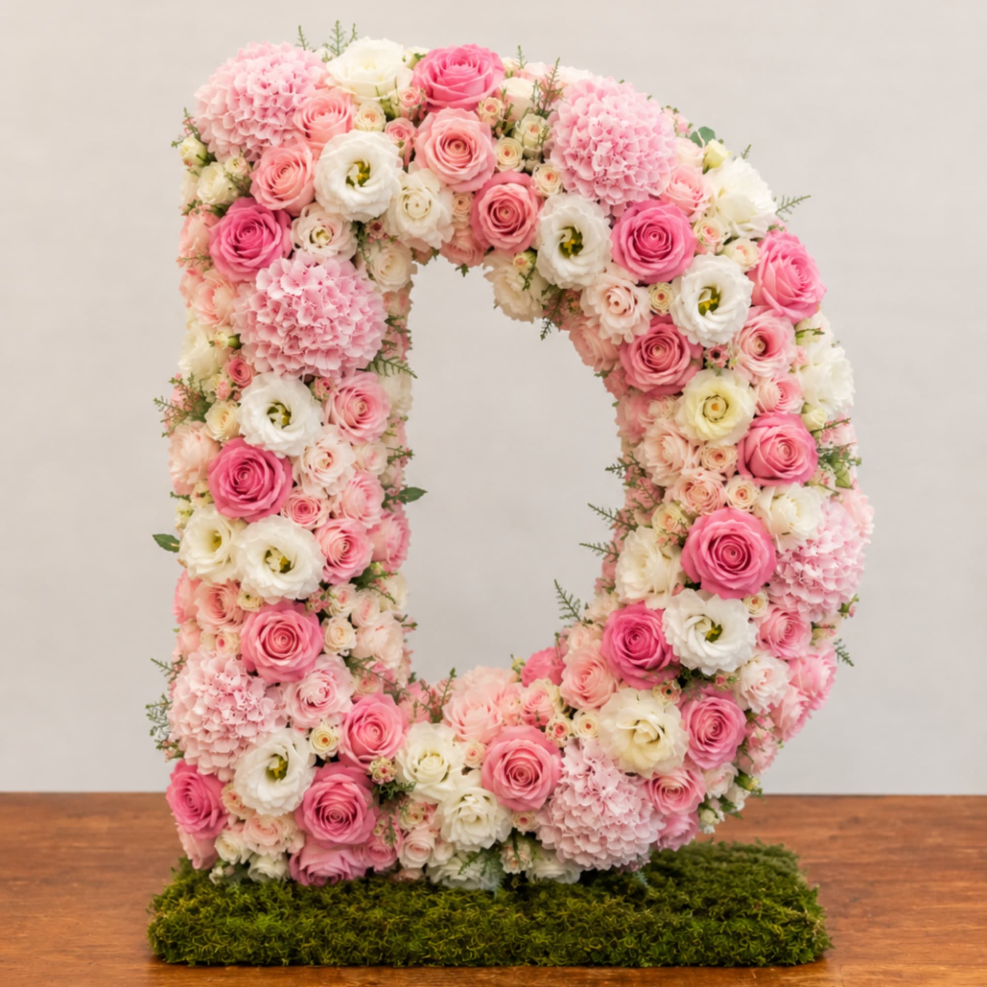 Pink and white floral letter O arrangement on a moss base