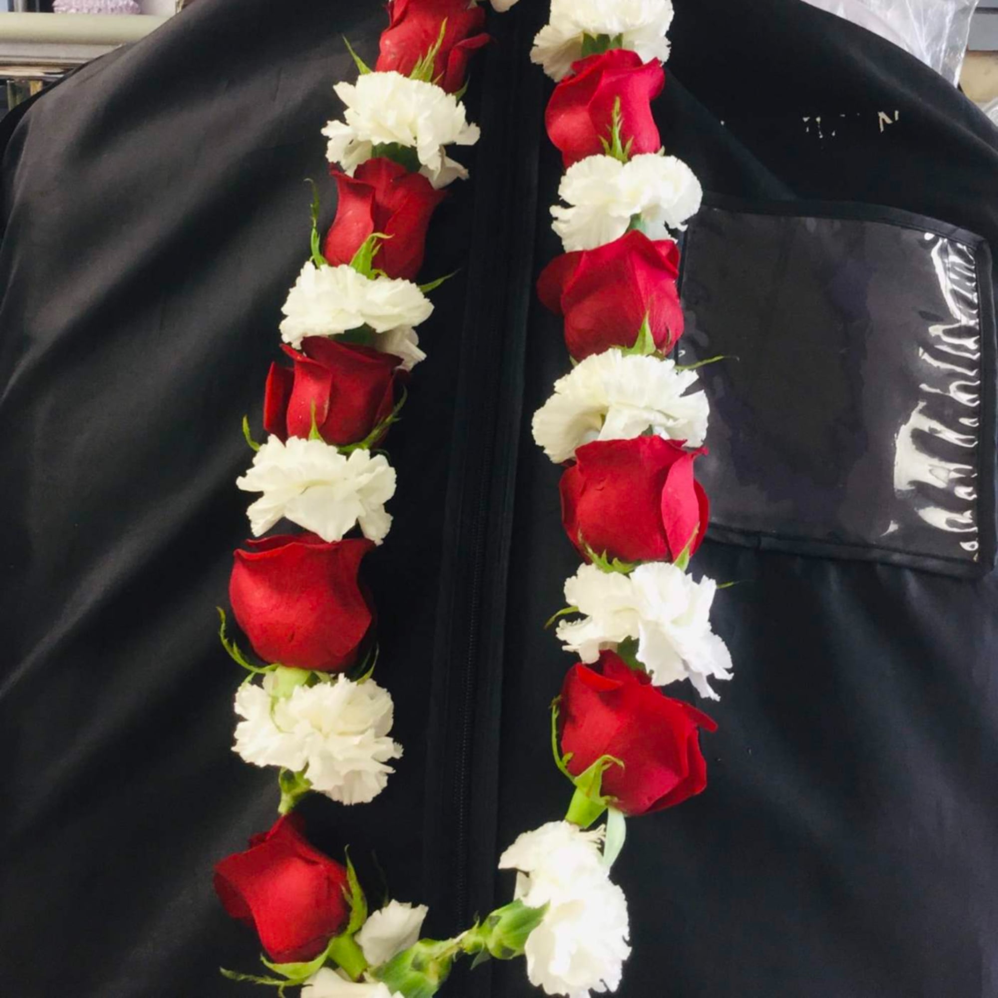 Red rose and white carnation garland laid on a black garment