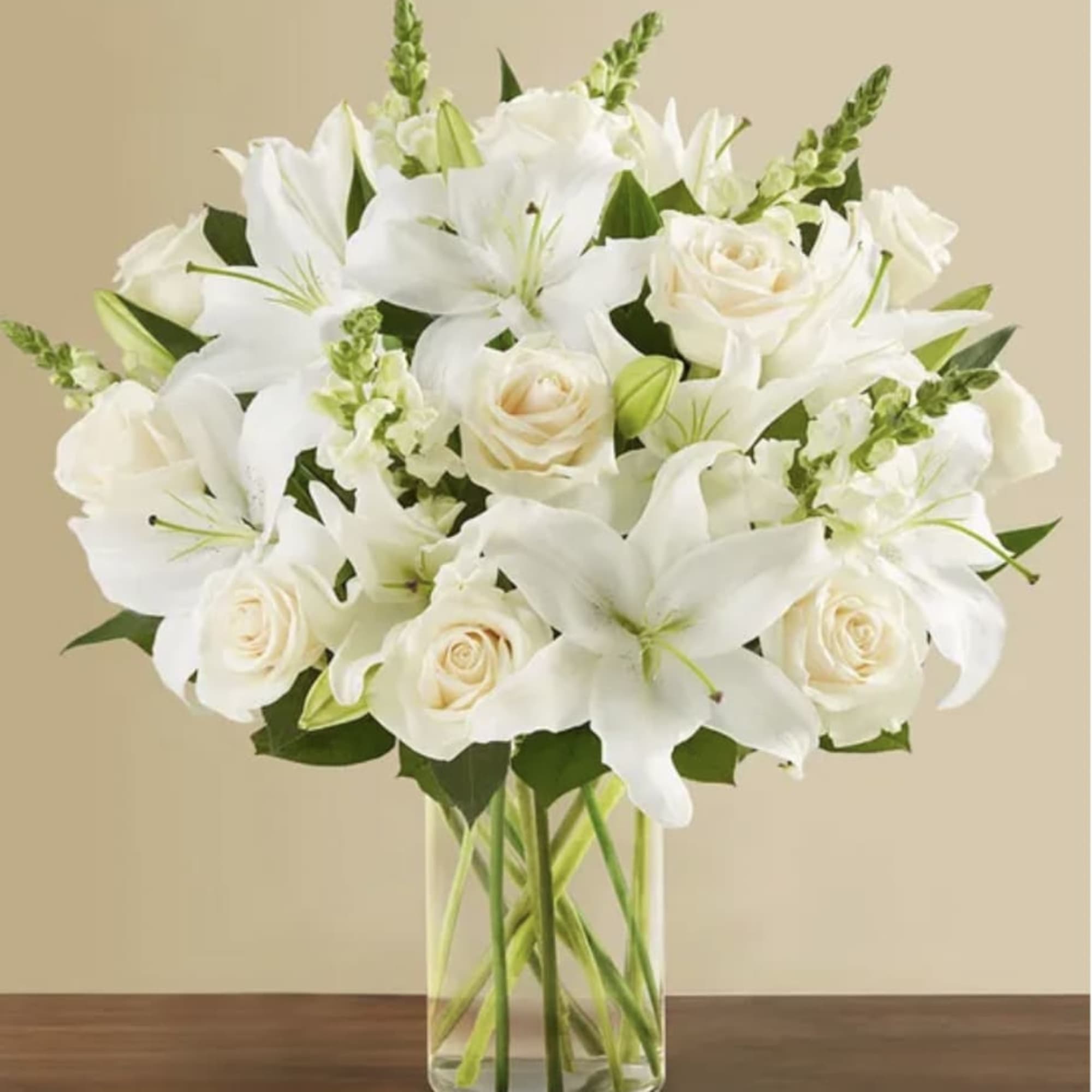 White lilies and cream roses arranged in a clear glass vase